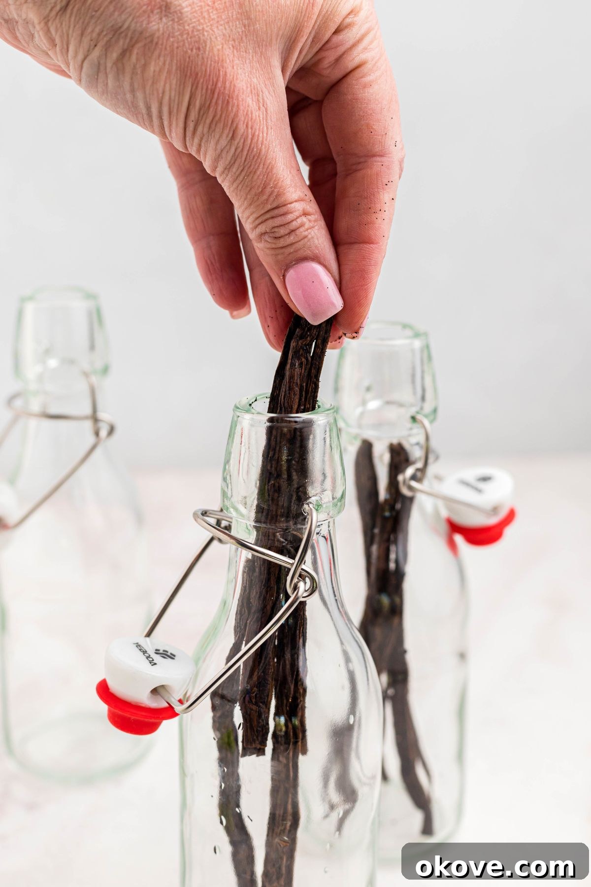 Handcrafted Vanilla Essence 5 Vanilla pods, after being sliced to reveal seeds, being carefully added into small glass bottles to make homemade vanilla extract.