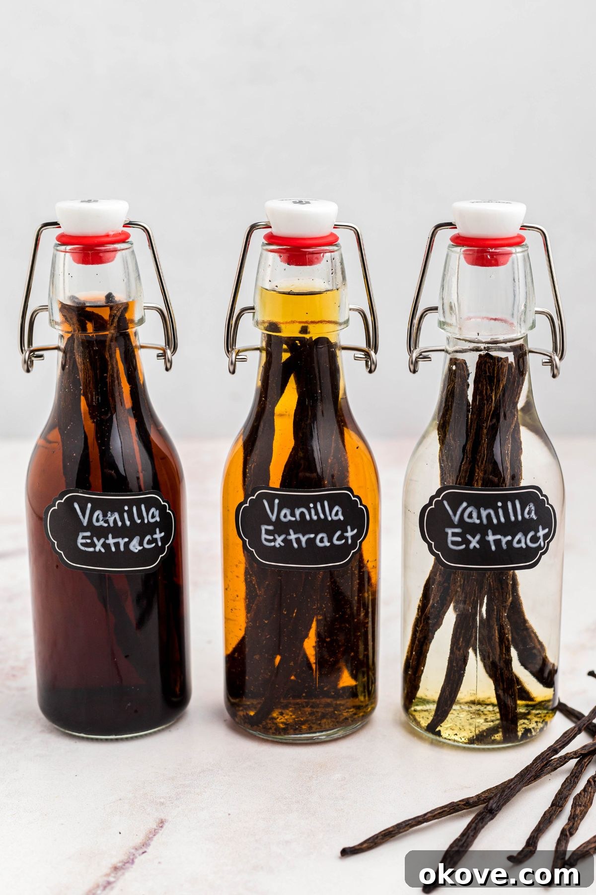 Handcrafted Vanilla Essence 7 Three bottles of homemade vanilla extract in different stages of infusion with vanilla pods, showcasing the color development over time.