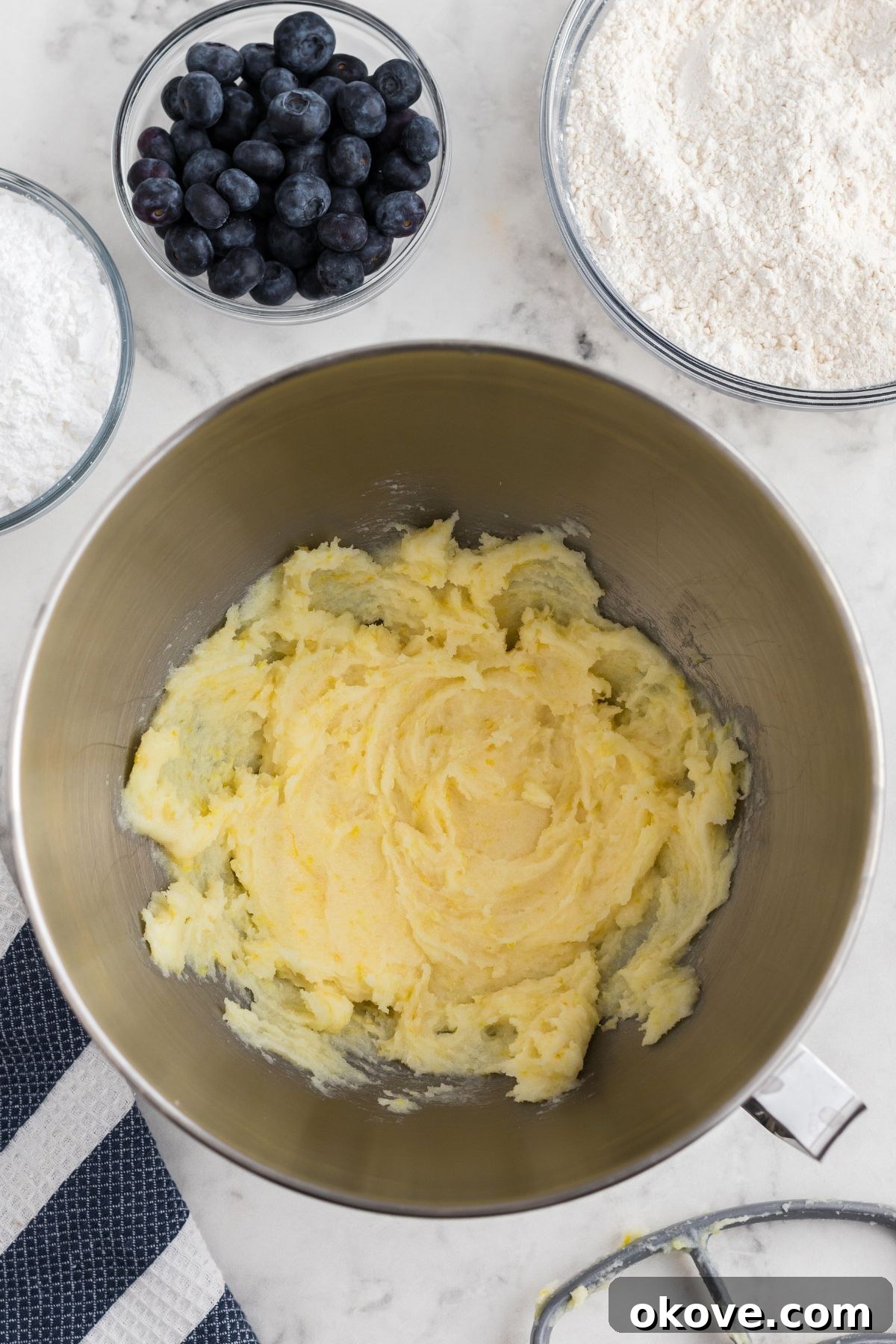 Tangy Blueberry Lemon Delights 5 Softened butter, granulated sugar, and lemon zest being creamed together in a large mixing bowl, creating a light and fluffy base for the cookie dough.