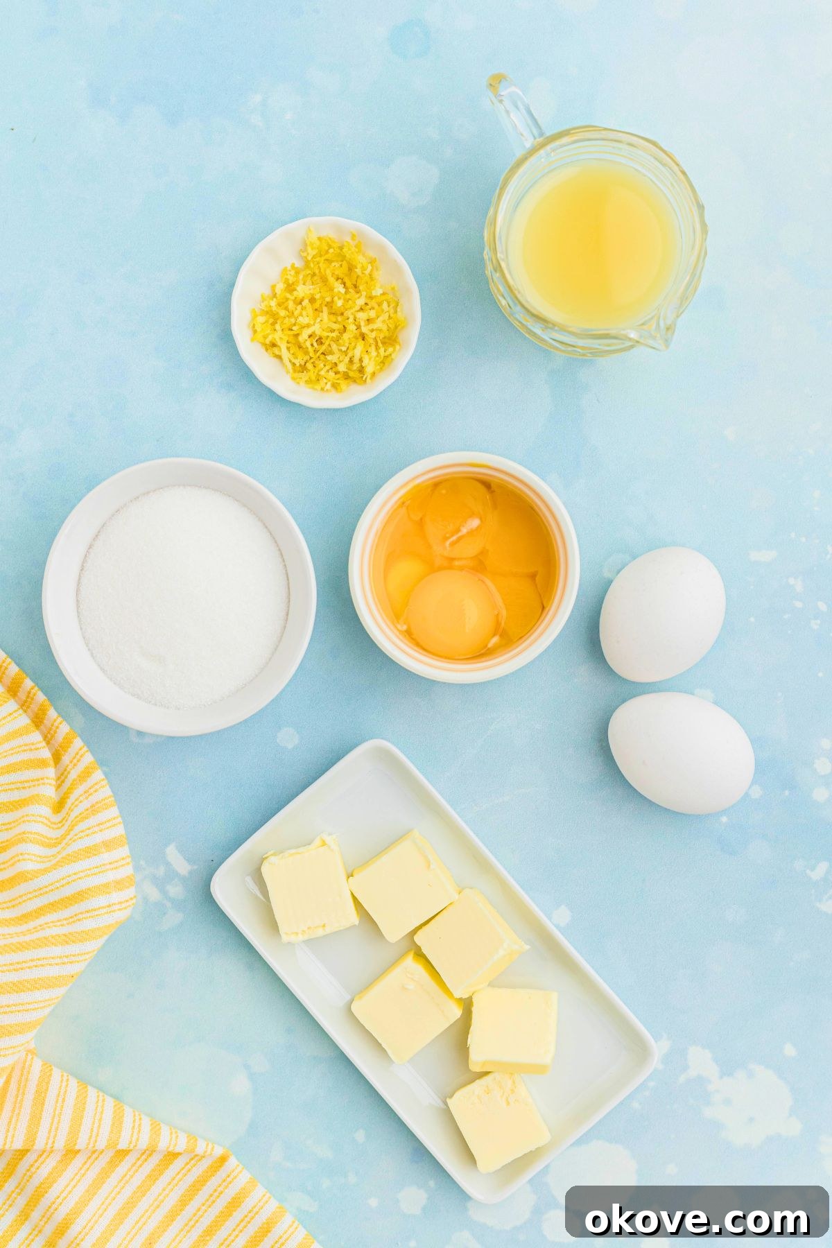Zesty Lemon Delight 3 All the essential ingredients for homemade lemon curd, measured into small bowls and neatly arranged on a light blue table.