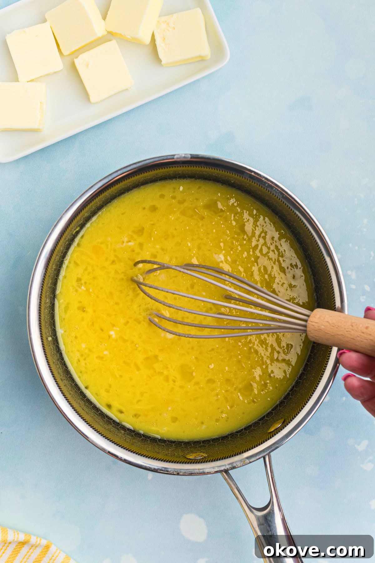 Zesty Lemon Delight 4 Eggs, sugar, lemon juice, and lemon zest being vigorously whisked together in a medium saucepan before heating.