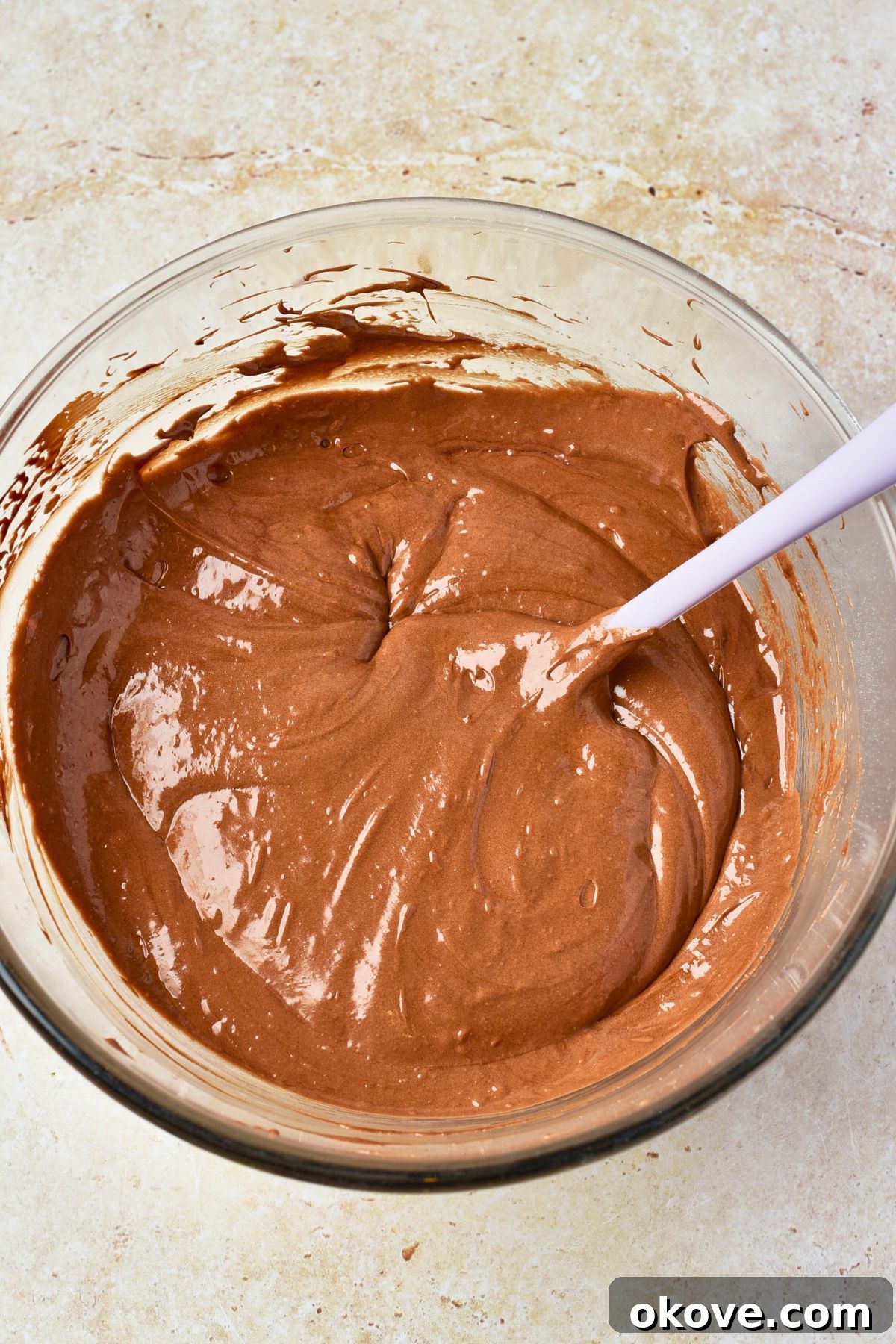 Molten Chocolate Dream 6 The fully mixed, rich, glossy chocolate cake batter resting in a clear glass mixing bowl, showcasing its smooth consistency.