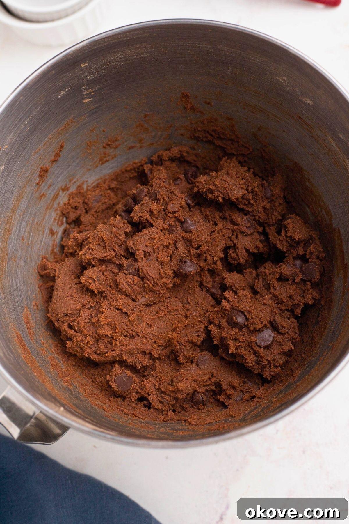 Luscious Double Chocolate Chip Cookies 6 Rich chocolate cookie dough with chocolate chips in a silver mixing bowl.