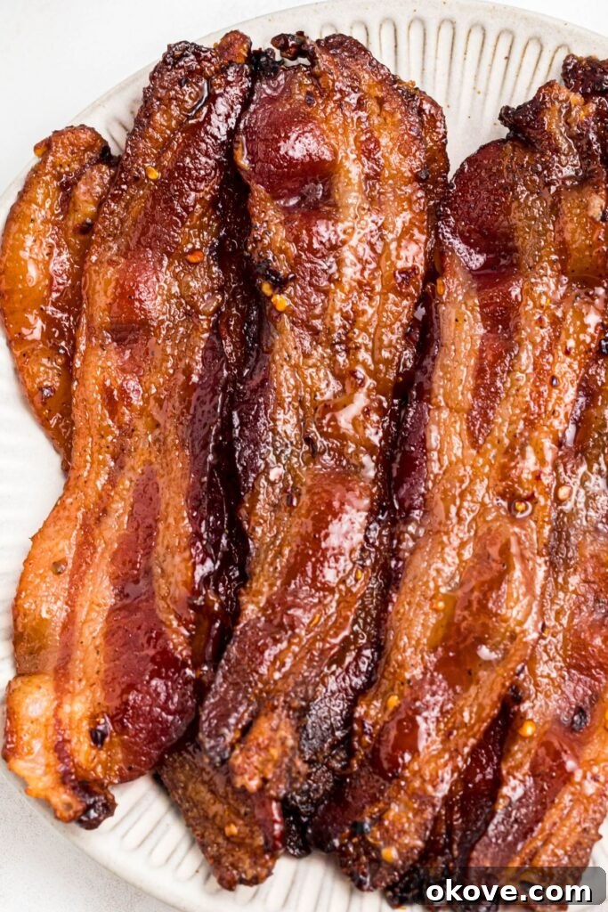Decadent Caramelized Bacon 8 Golden juicy millionaire bacon stacked on a white plate.