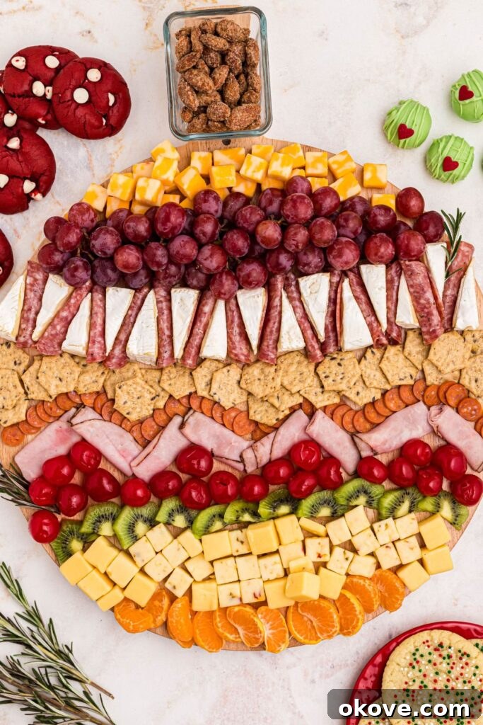 A complete and vibrant Christmas charcuterie board overflowing with various fruits, meats, cheeses, and accompanying treats on the table.