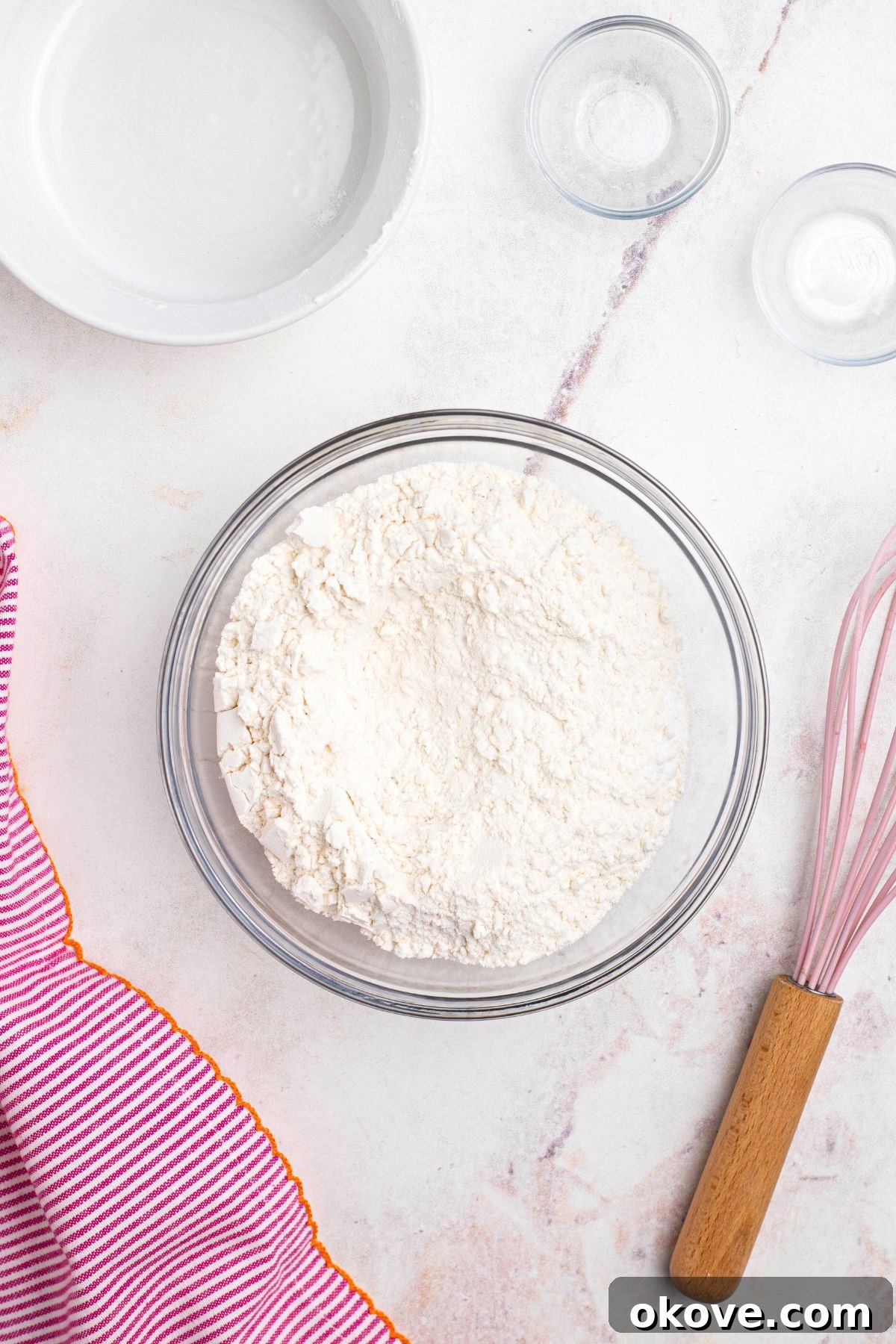 Flour and other dry ingredients mixed in a clear glass bowl.