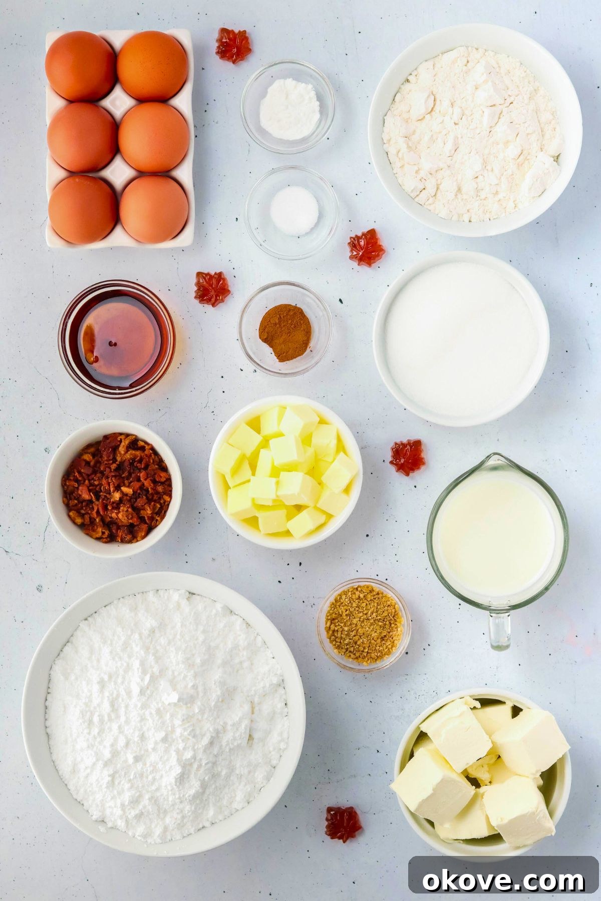 All the necessary ingredients to bake delicious maple bacon cupcakes, neatly measured and arranged on a pristine white marble countertop.