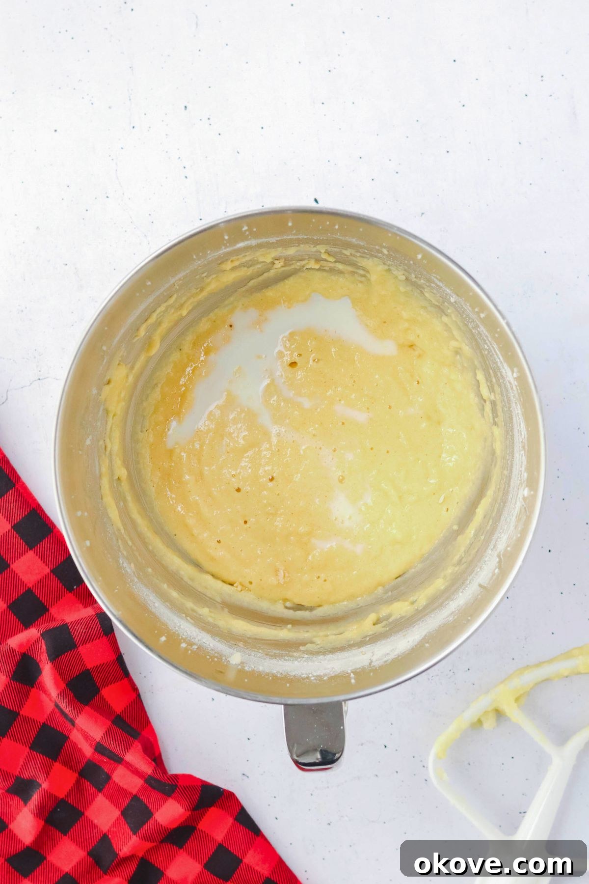 Smooth, creamy cupcake batter perfectly mixed in a shiny silver mixing bowl, ready for the next step.