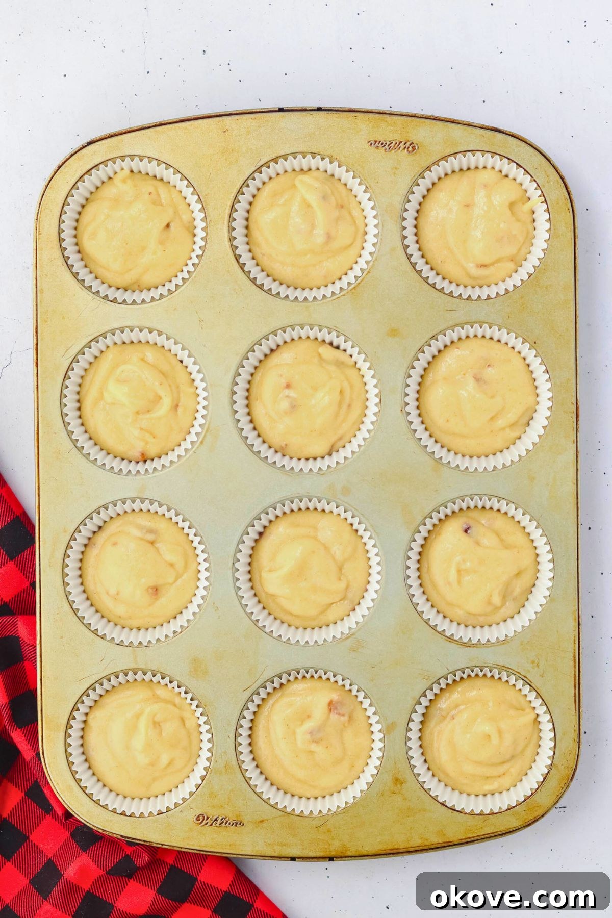 Cupcake batter carefully poured into individual liners within a baking pan, poised for baking.
