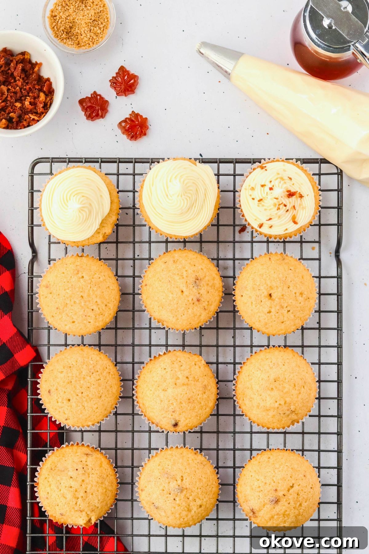 A beautifully frosted maple bacon cupcake on a black stand, showcasing the creamy frosting adorned with crumbled bacon pieces.