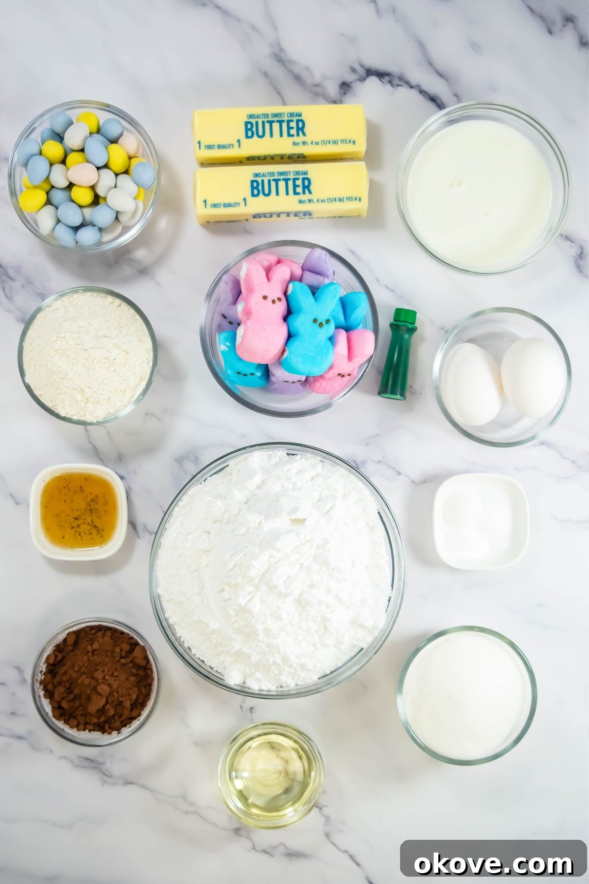 Colorful Peeps Cupcake Delights 3 Various cupcake ingredients, including flour, sugar, cocoa, eggs, and milk, portioned in small bowls on a marble surface.