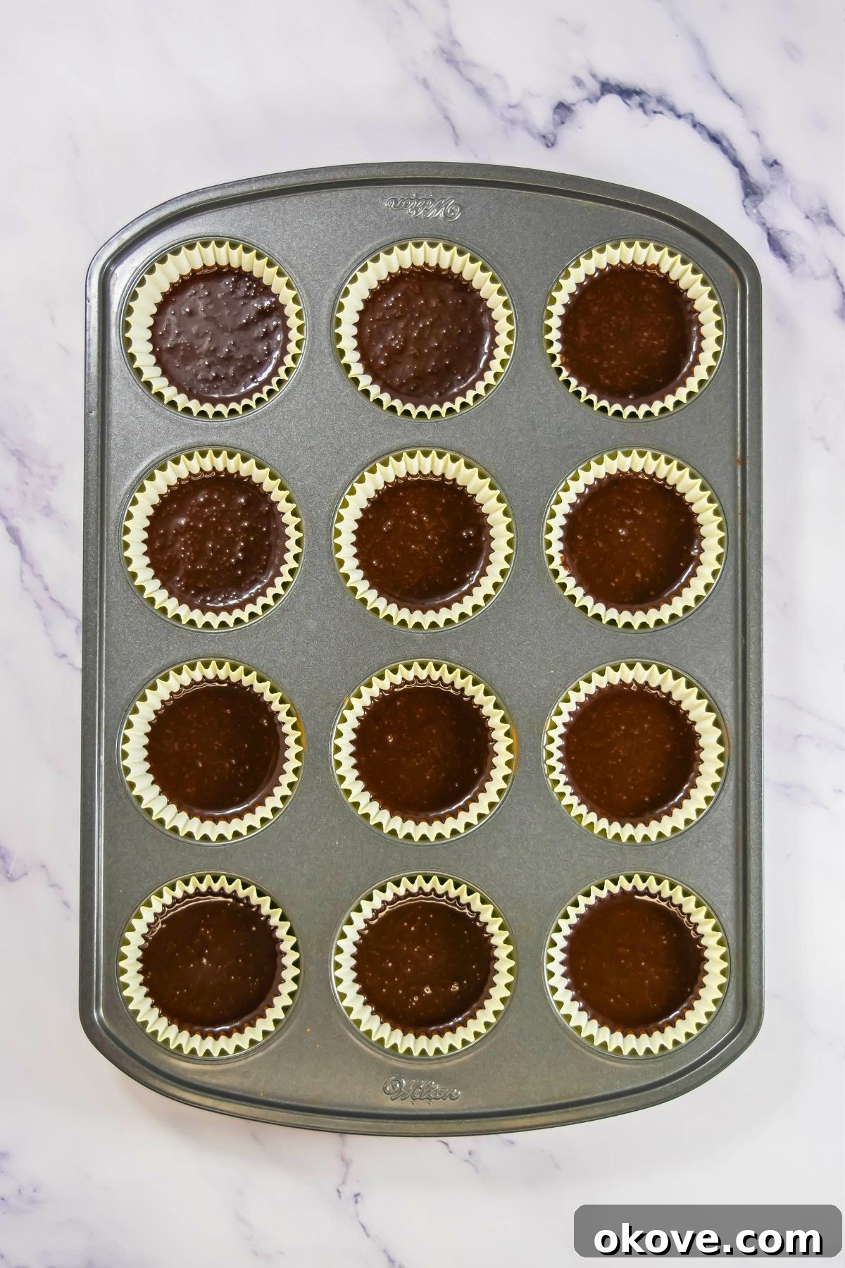 Colorful Peeps Cupcake Delights 6 Cupcake liners filled with chocolate batter in a muffin tin, prepared for baking.
