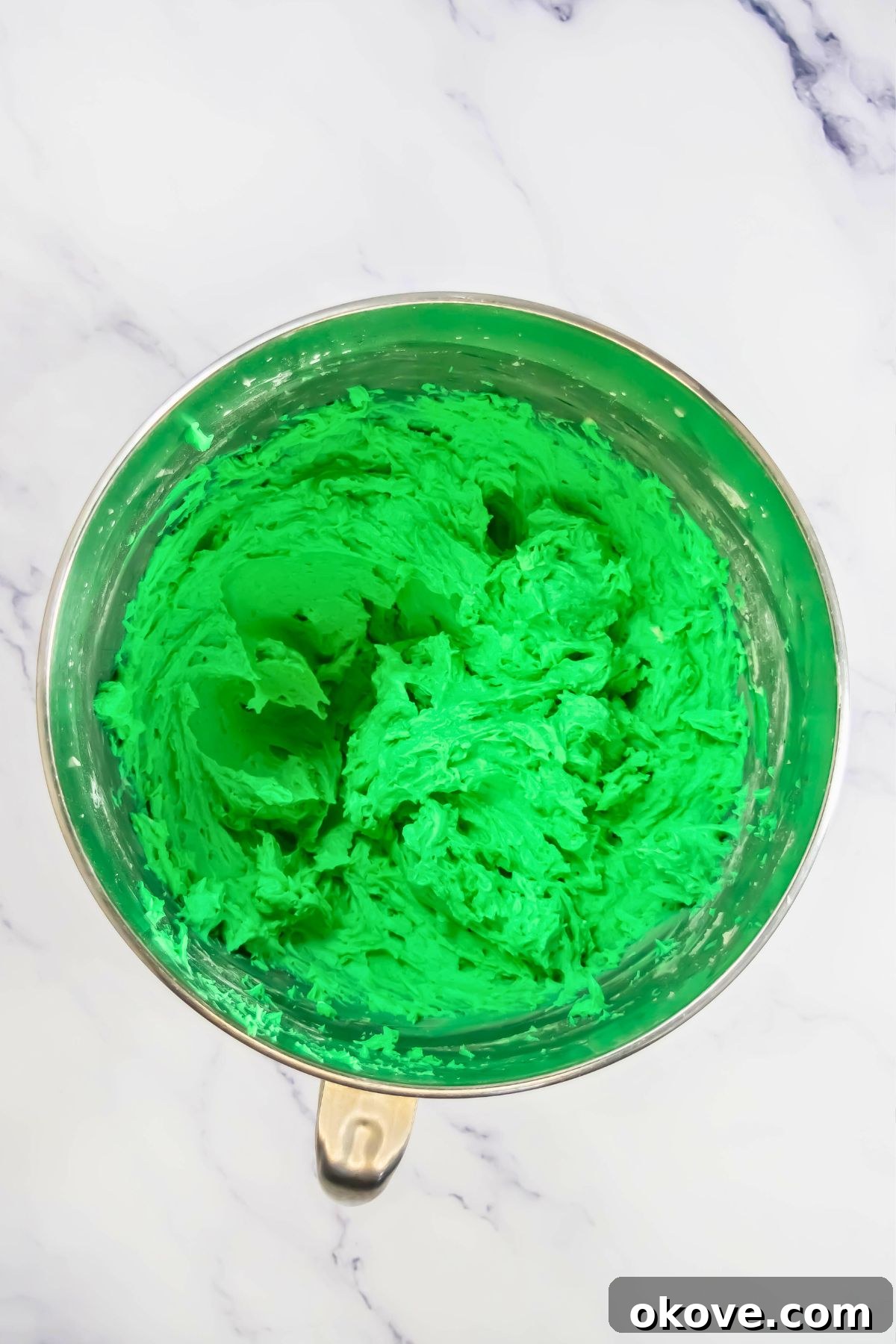 Colorful Peeps Cupcake Delights 7 Vibrant green buttercream frosting in a silver mixing bowl, whipped to perfection.