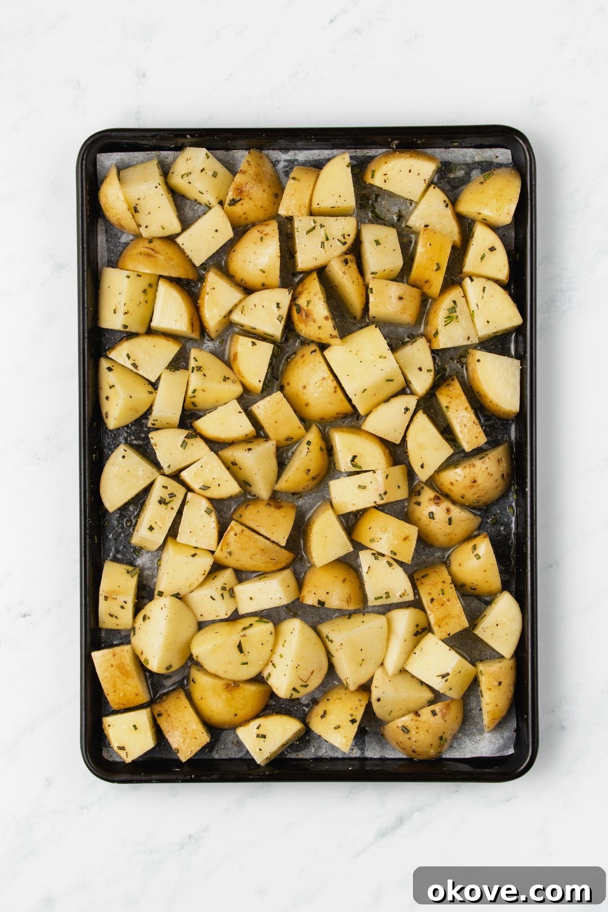 The Ultimate Roasted Spuds 5 Seasoned potato chunks spread in a single layer on a baking sheet, ready for roasting.