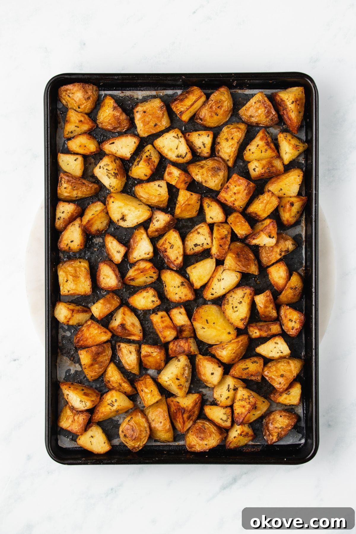 The Ultimate Roasted Spuds 6 Golden, crispy roasted potatoes fresh out of the oven on a baking sheet.