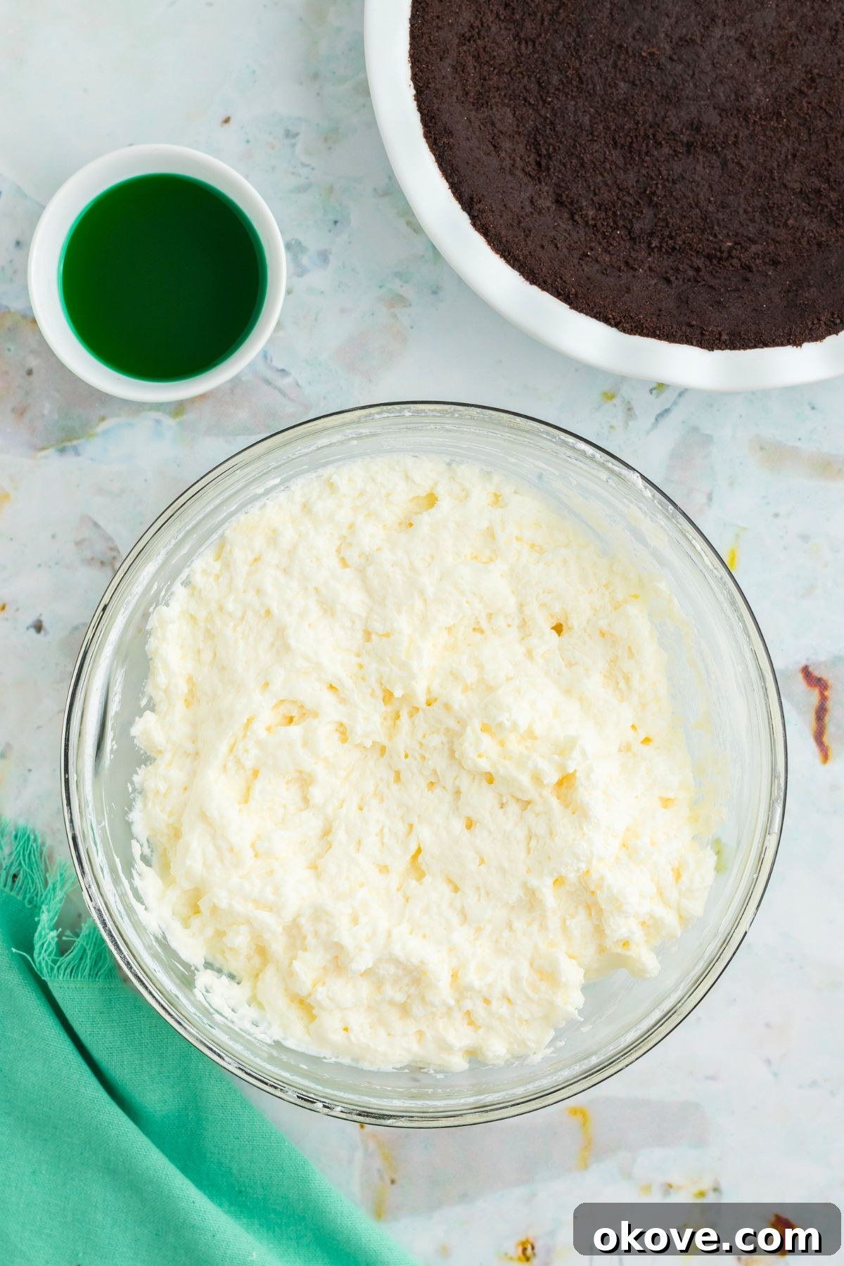 Minty Green Dream Pie 7 Fluffy, stiffly whipped heavy cream in a clear glass mixing bowl, ready to be incorporated into the pie filling, showcasing its perfect texture.