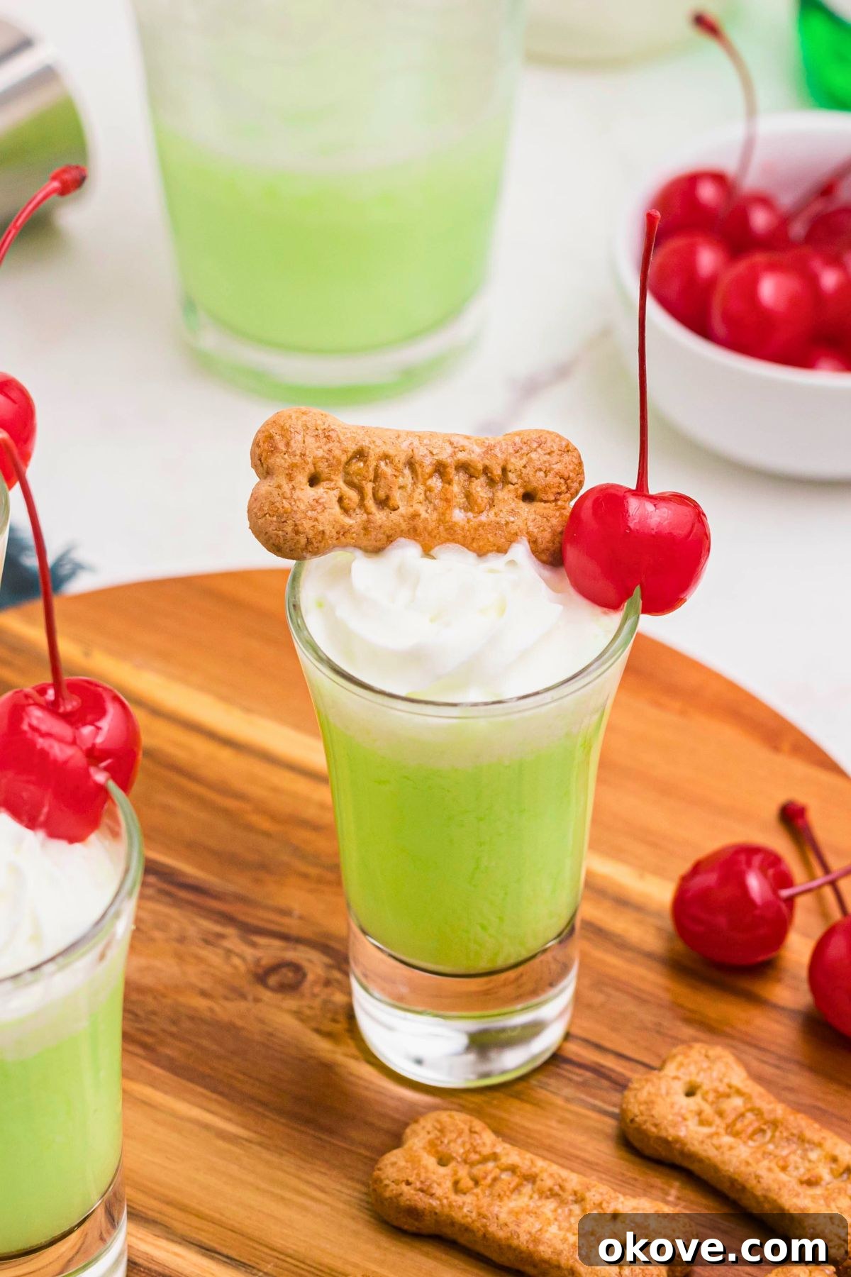 Green shot in a shot glass topped with a cherry and whipping cream. 