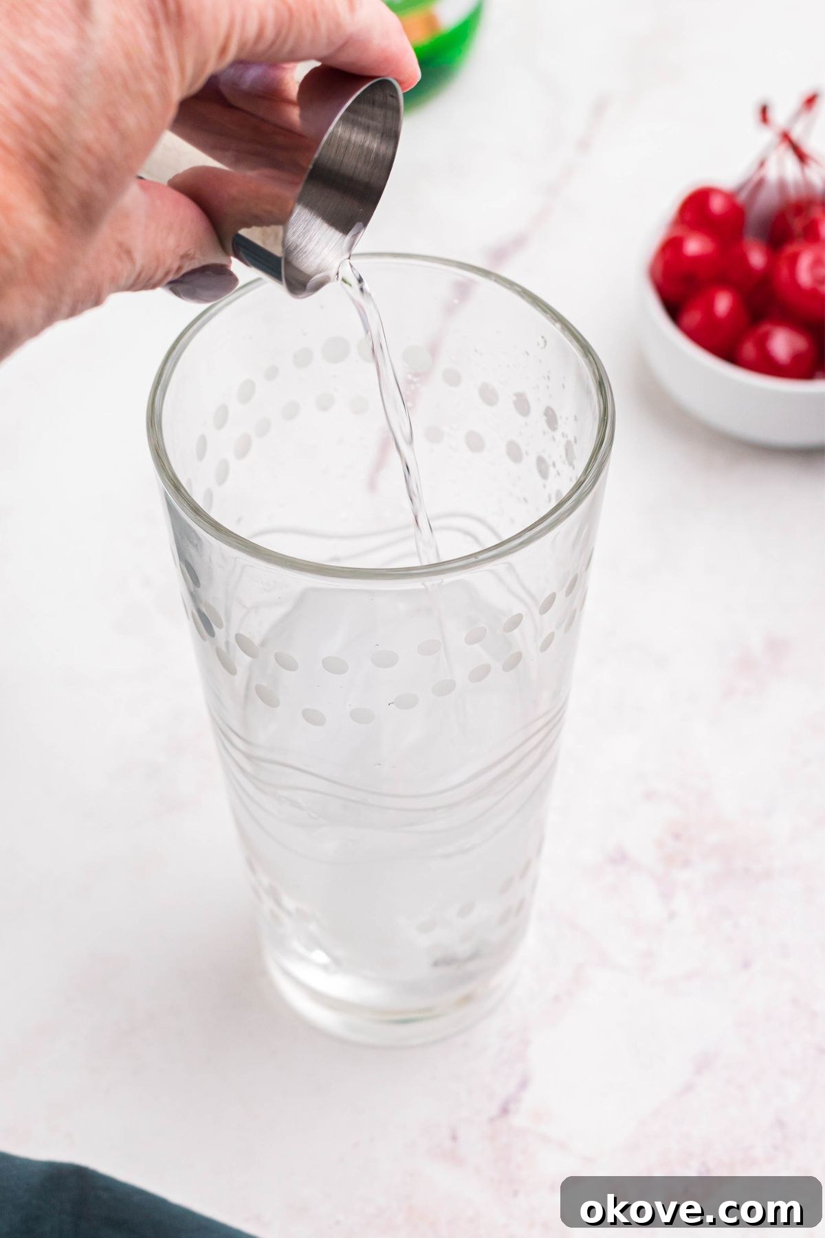 Rum being poured into clear glass cocktail shaker. 