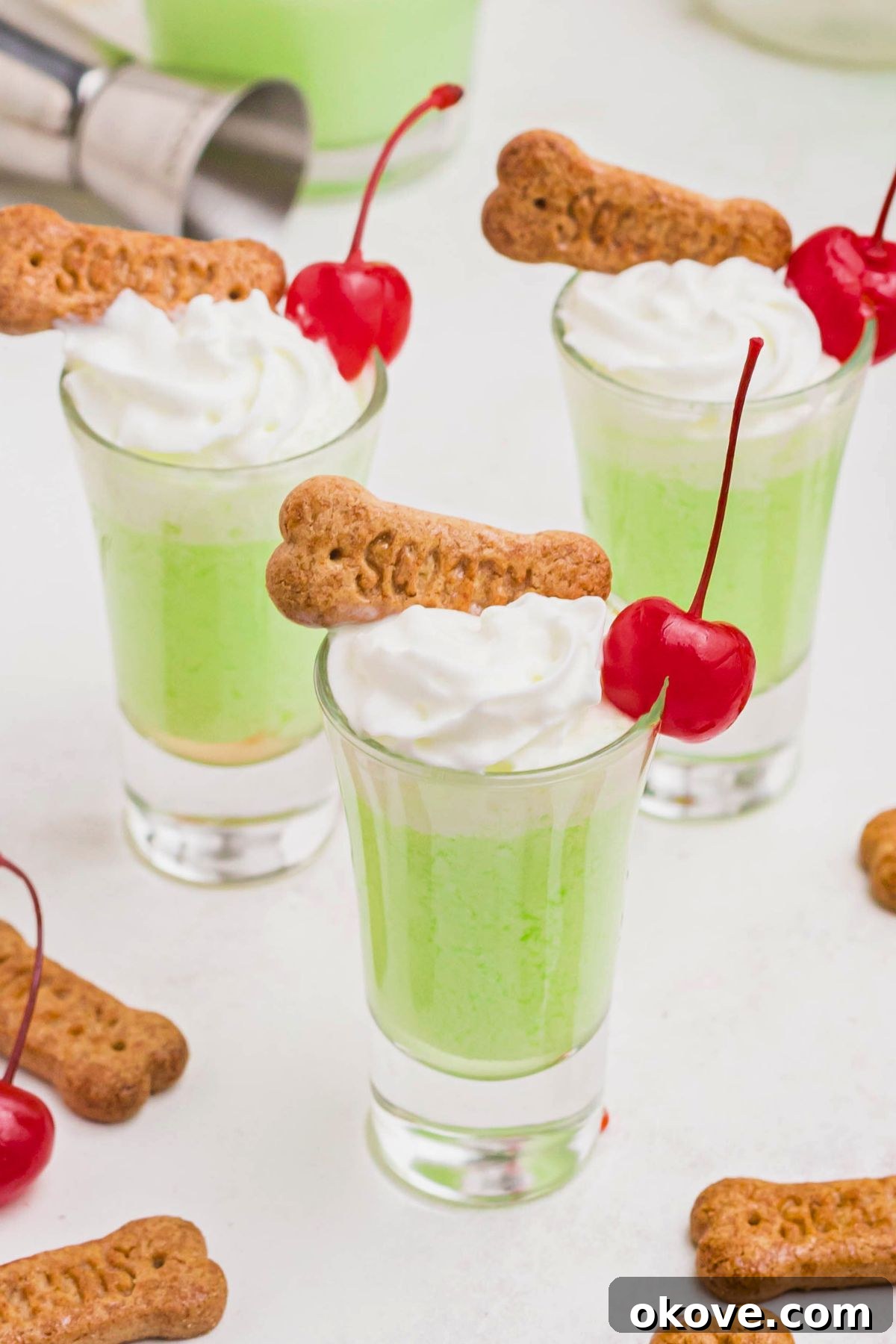Green scooby snack shot in a small glass, topped with whipping cream and a cherry. 