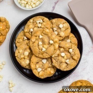Golden white chocolate chip cookies on a black plate