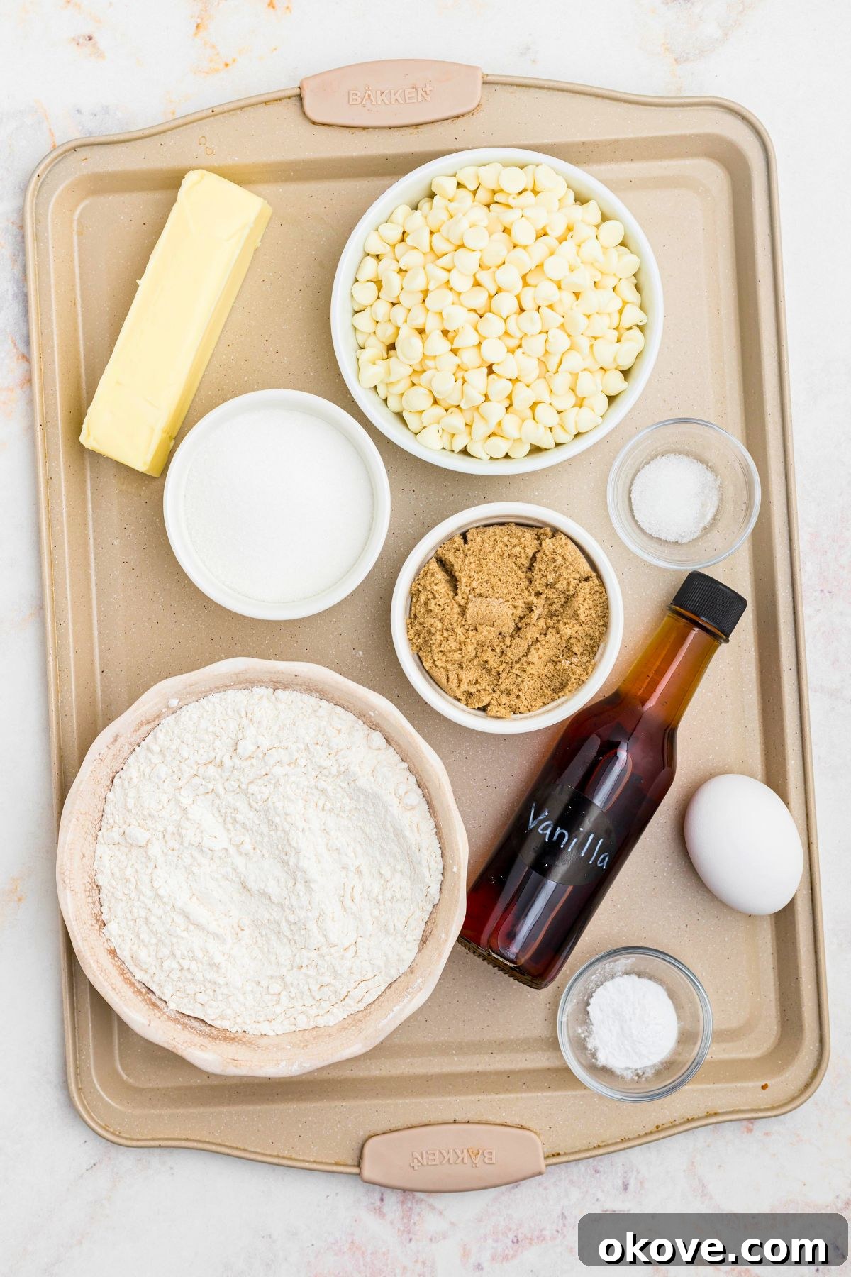 All the necessary ingredients for making white chocolate chip cookies, neatly measured and placed in small individual bowls on a kitchen counter.