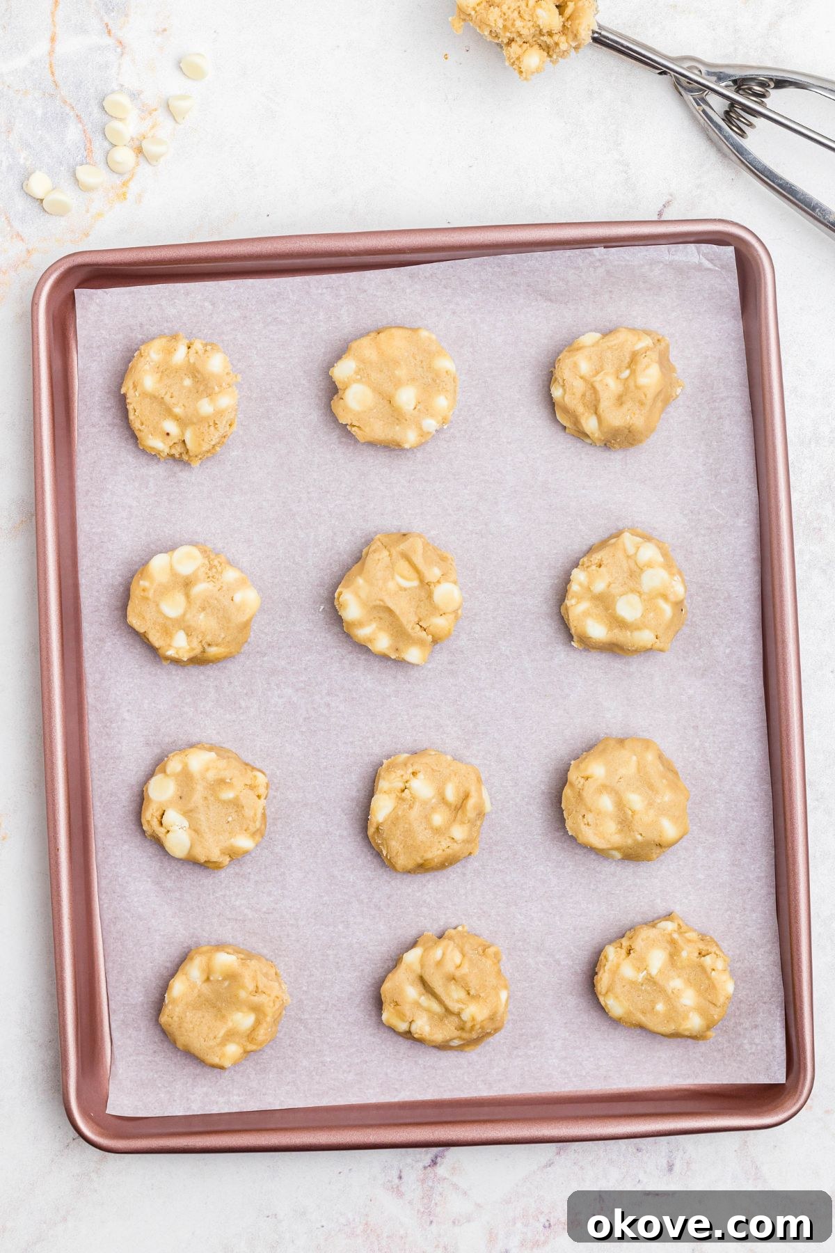 Unbaked cookie dough formed into small, even balls and placed on a vibrant pink baking sheet, perfectly spaced for baking.