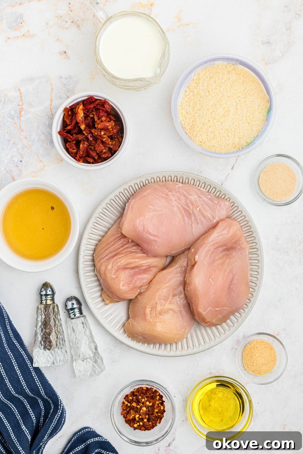 Say Yes Chicken 3 Ingredients needed to make Marry Me Chicken, meticulously measured into small bowls and artfully arranged on a elegant marble countertop.