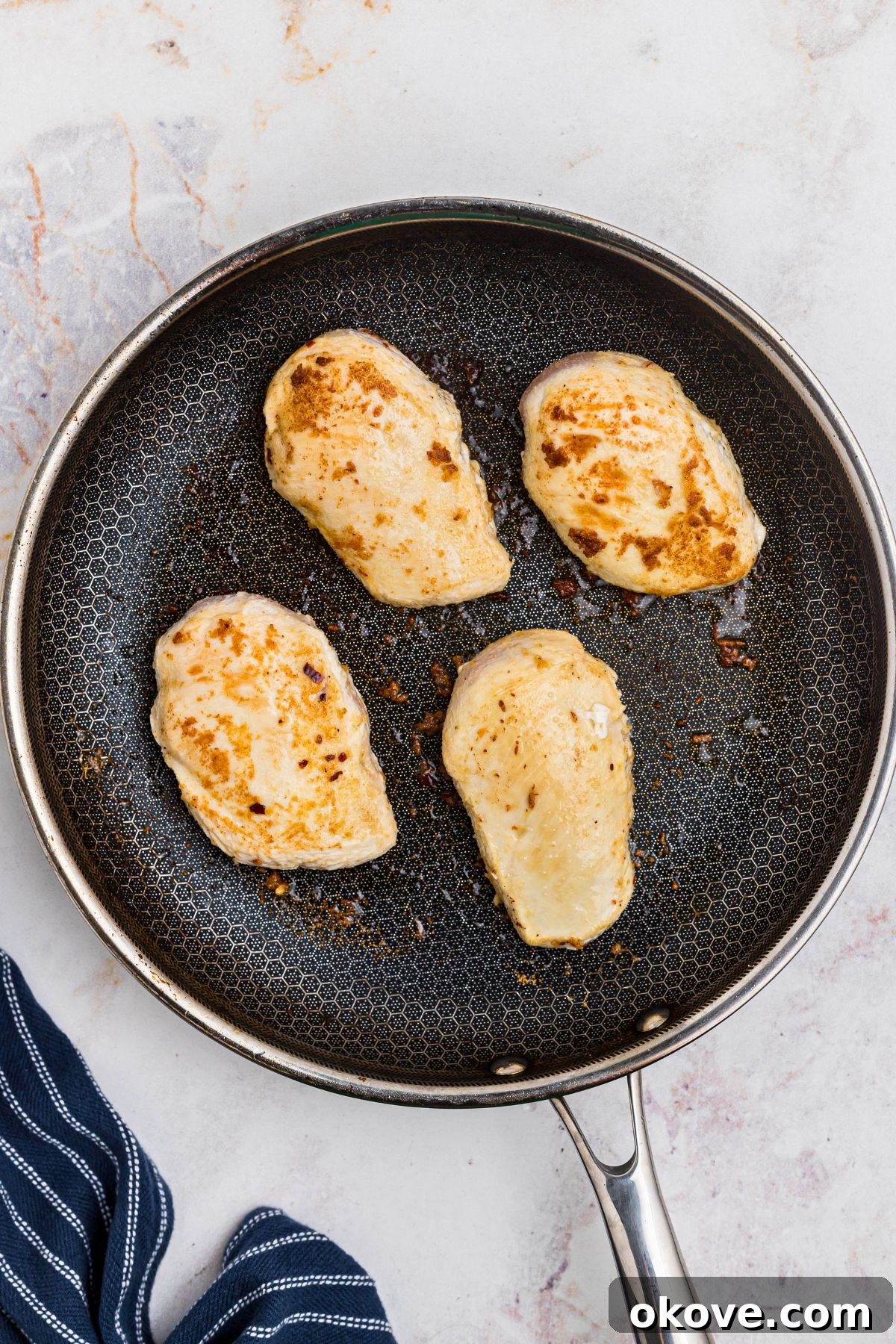 Say Yes Chicken 5 Four golden-brown chicken breasts perfectly seared in a large, hot skillet, ready to be removed.