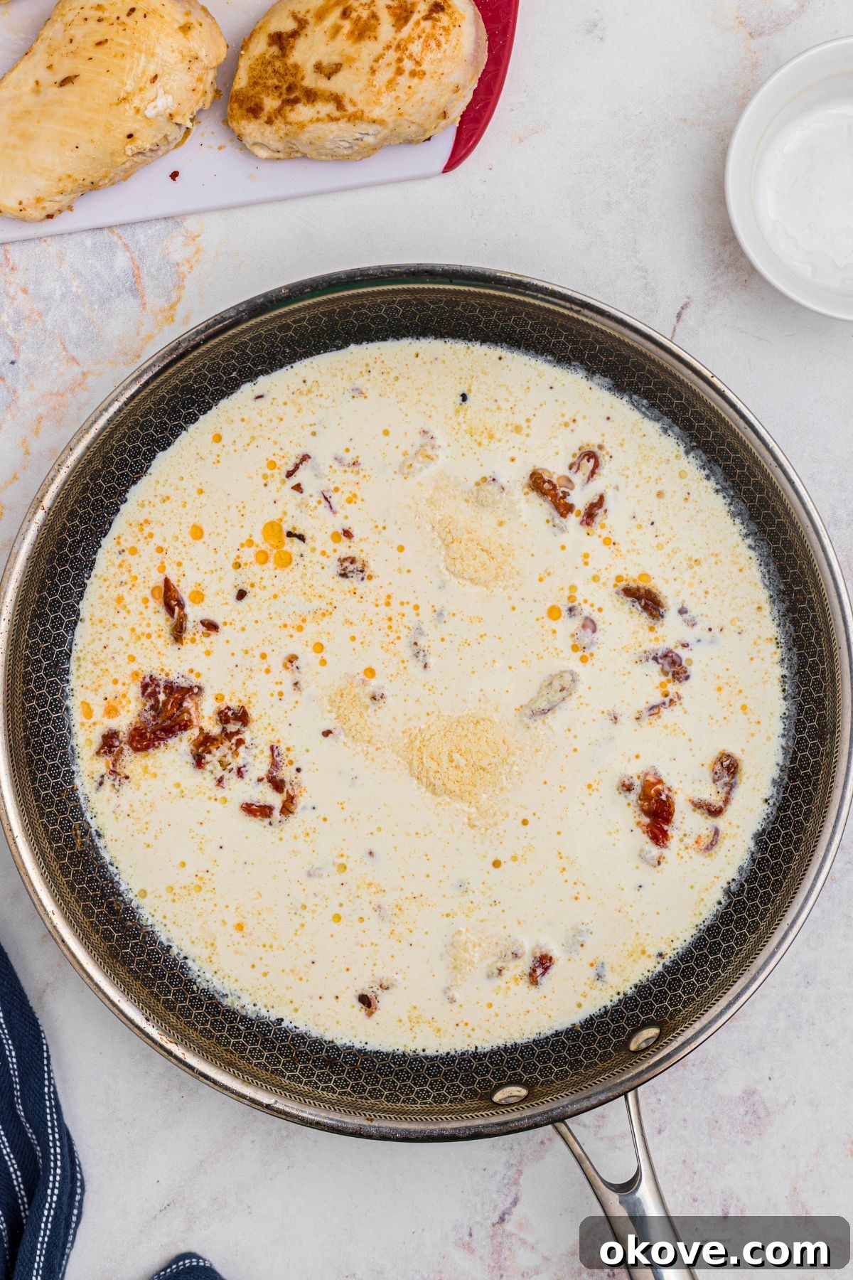 Say Yes Chicken 6 Rich heavy cream and grated Parmesan cheese being stirred into the skillet with sun-dried tomatoes, forming the luscious sauce.
