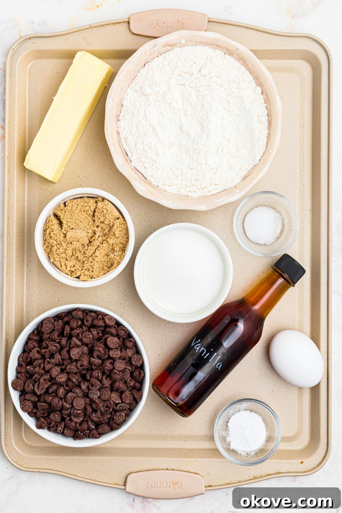 Warm Chocolate Chip Indulgence 3 Ingredients needed to make cookies, including flour, sugars, butter, eggs, and chocolate chips, carefully measured on a baking sheet.