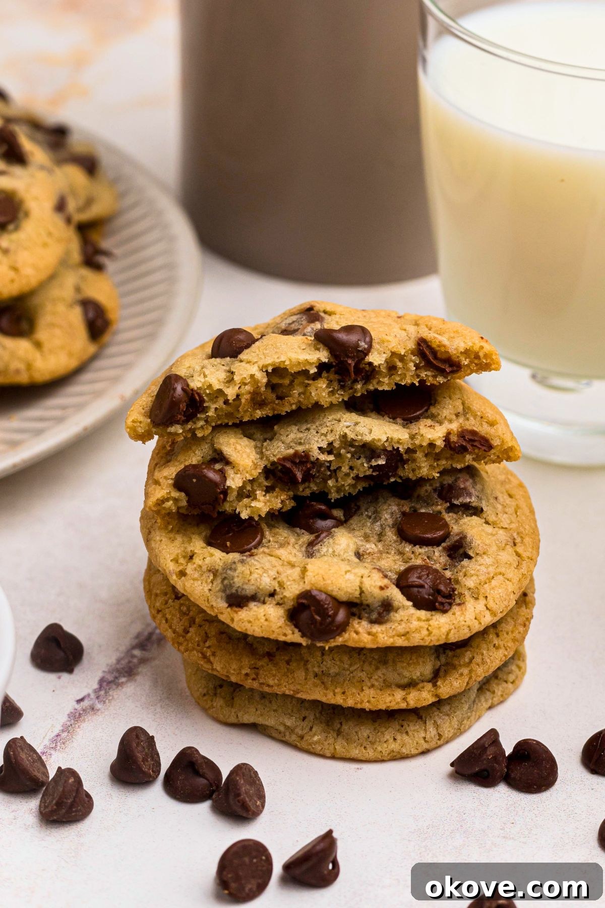 Warm Chocolate Chip Indulgence 8 A stack of golden brown chocolate chip cookies on a marble table, with a glass of milk and scattered chocolate chips in the background.