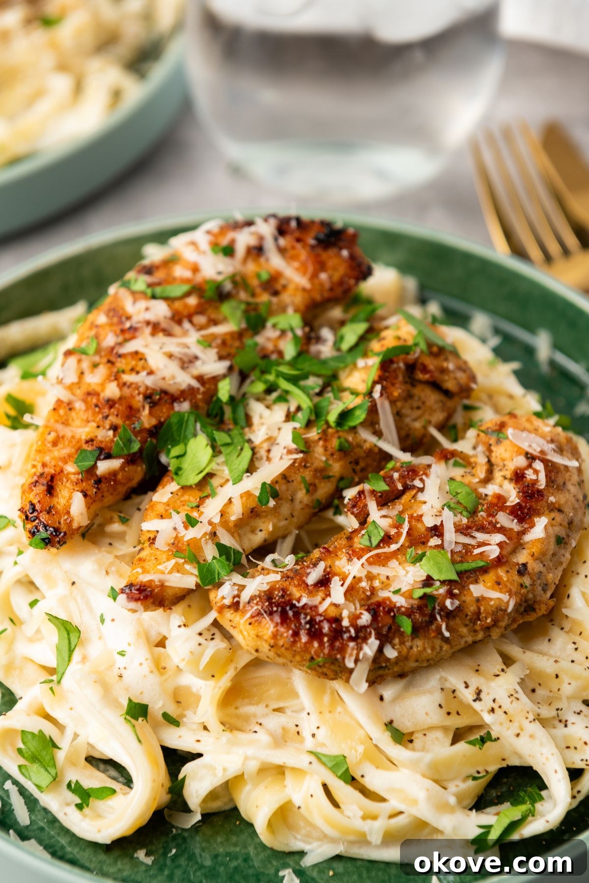Golden seasoned chicken on top of fettuccine tossed with creamy Alfredo sauce, garnished with fresh parsley.