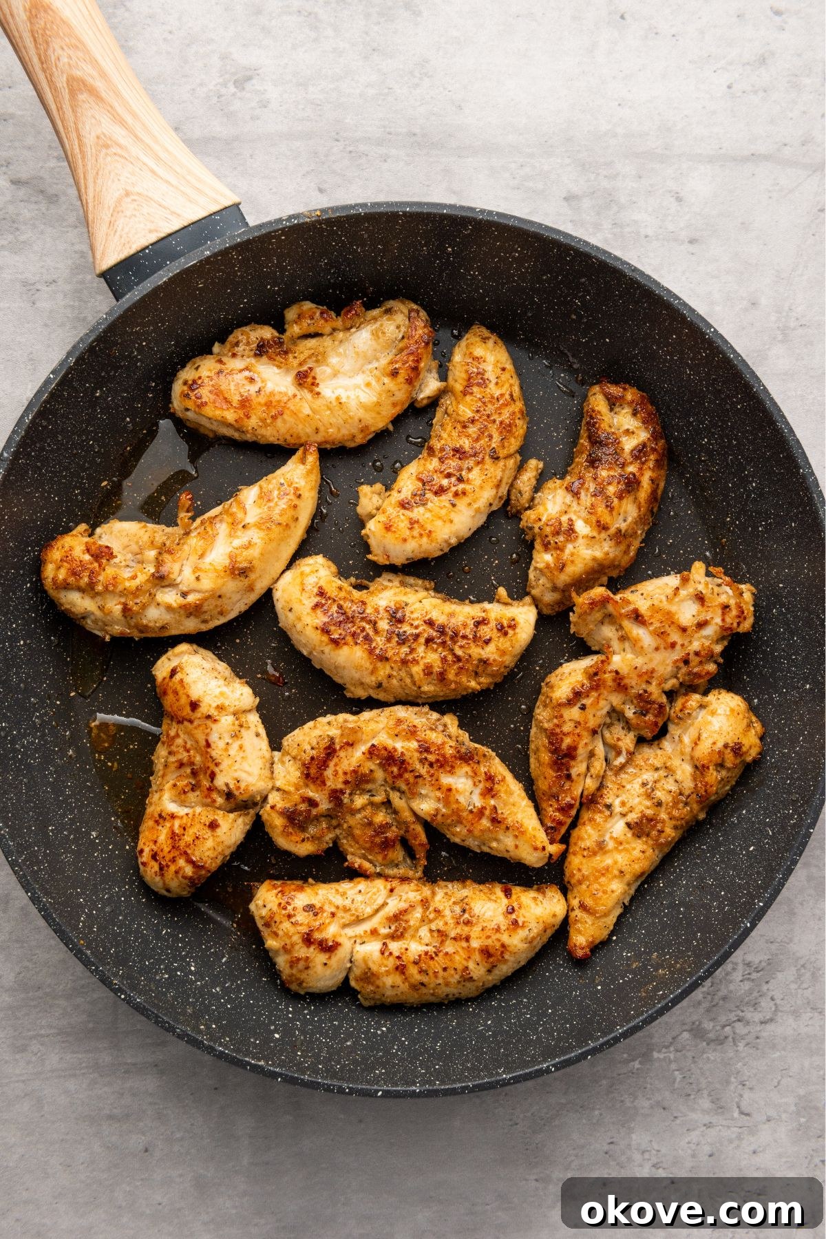Perfectly seared, golden-brown Cajun chicken pieces resting in a large skillet after cooking.