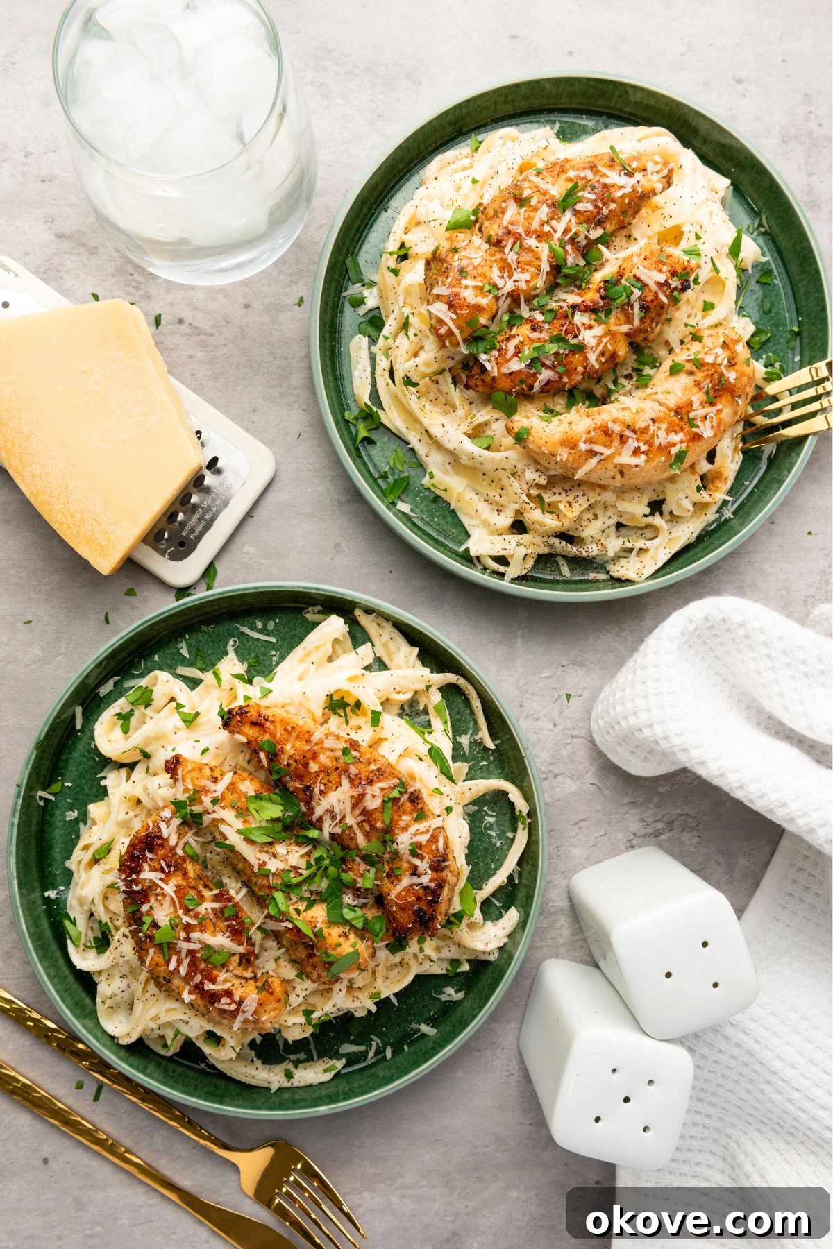Plated Cajun chicken on a bed of fettuccine alfredo, served on vibrant green plates, garnished with fresh herbs.