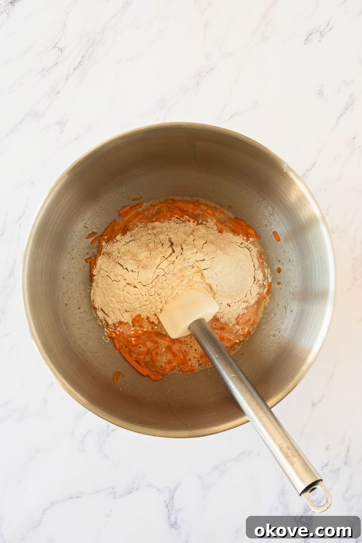 Spiced Carrot Roulade 4 Finely shredded carrots mixed into the wet cake ingredients in a large silver mixing bowl.