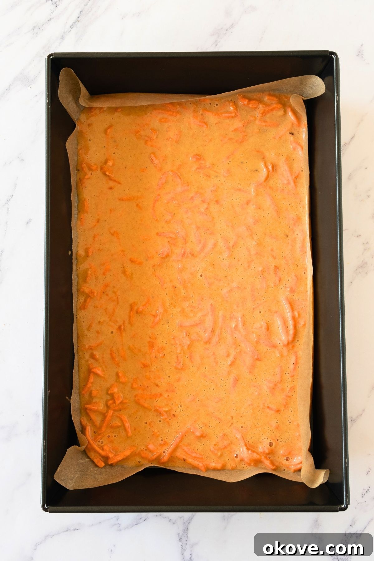 Spiced Carrot Roulade 5 Smooth carrot cake batter evenly spread in a baking pan, ready for the oven.