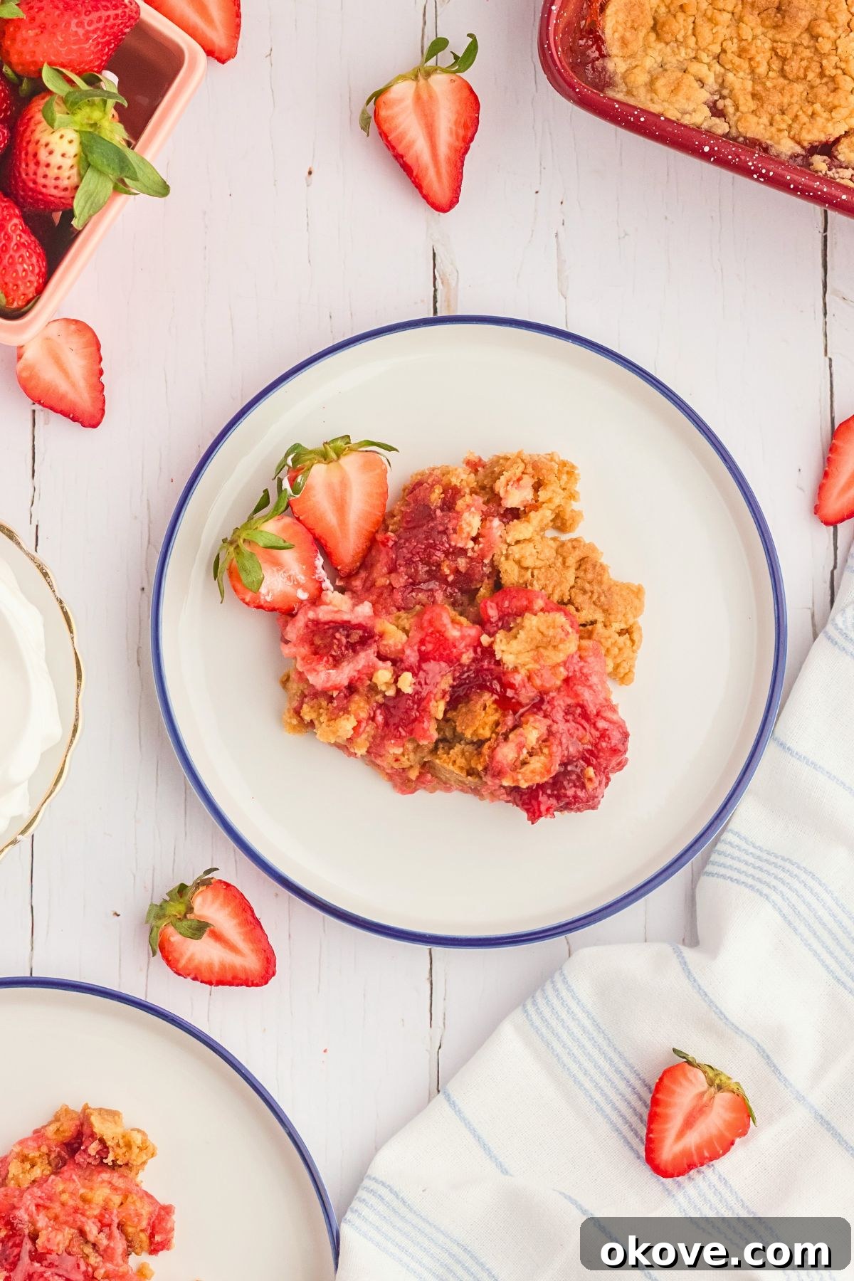 Effortless Strawberry Delight 8 A perfect slice of strawberry dump cake on a white plate, adorned with fresh strawberry slices, a truly appetizing sight.