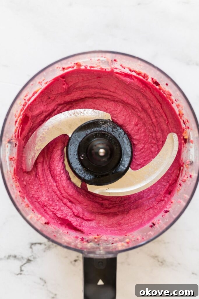 Vibrant Beet Hummus 6 Smooth and creamy pink beet hummus freshly blended in a food processor, ready to be transferred to a serving dish.