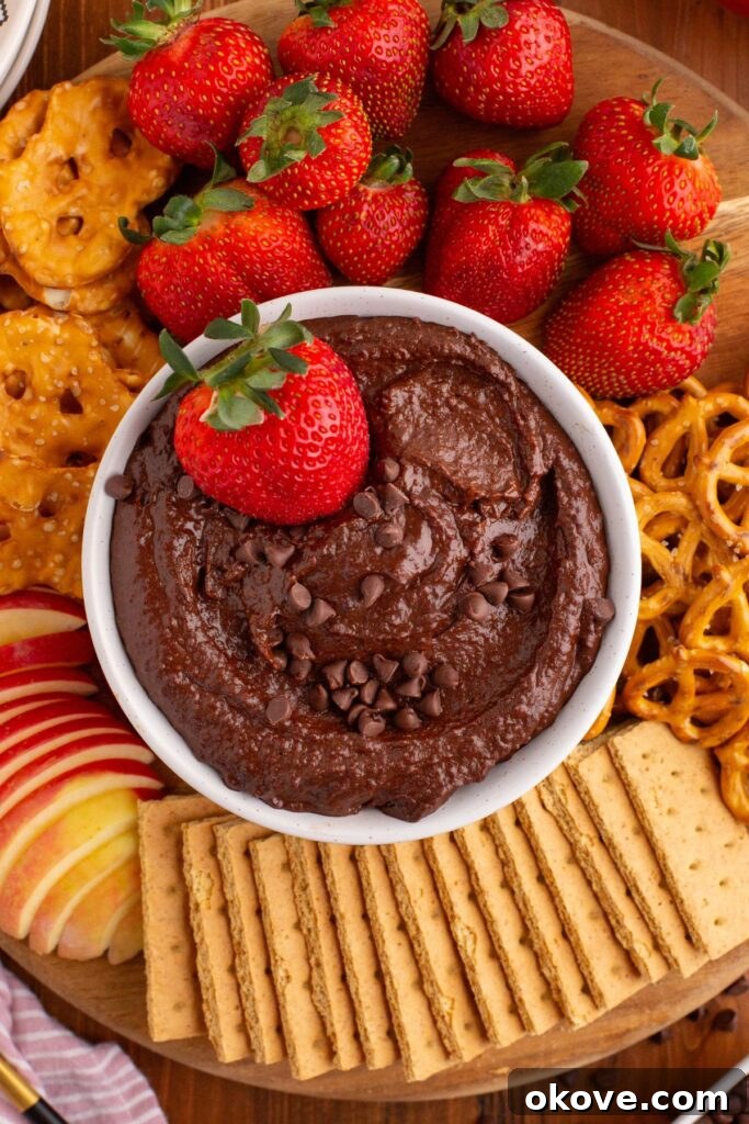 Decadent Chocolate Hummus 2 Smooth and creamy chocolate hummus in a white bowl with crackers and fruit on a serving platter. A visually appealing dessert dip ready for serving.