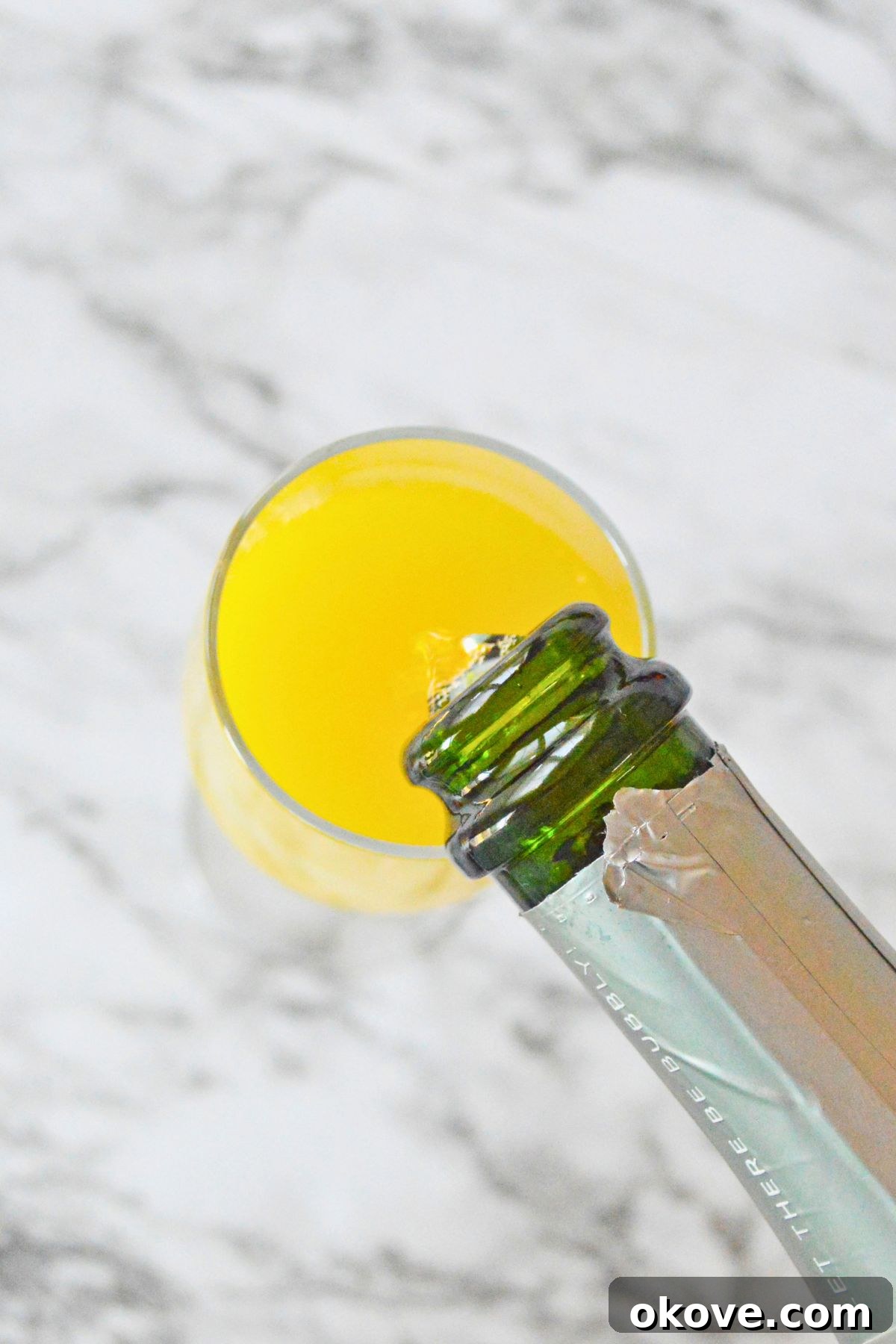 Sunrise Peach Sparkler 4 Champagne being carefully poured into a glass on a elegant marble table, ready to complete a delicious mimosa.