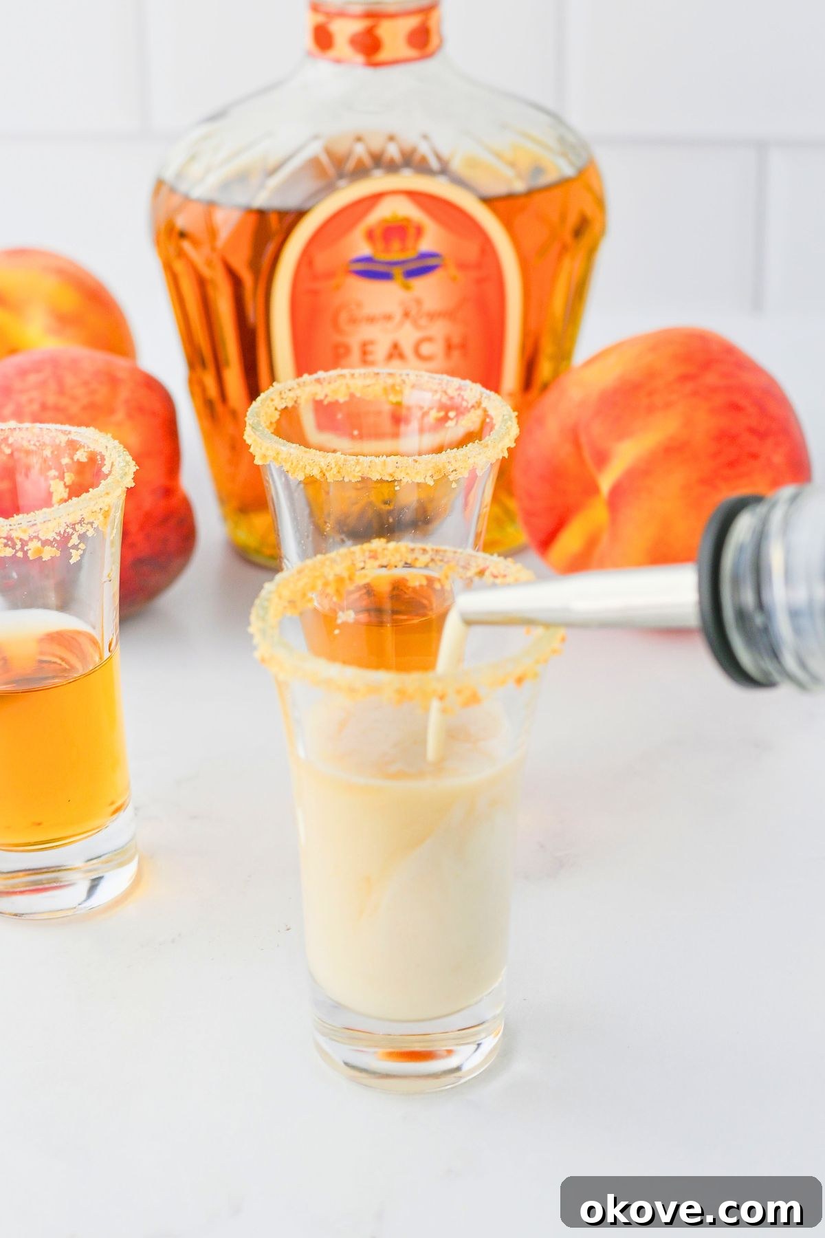 Whiskey being carefully mixed with RumChata in a small shot glass, showing the creamy texture of the drink before serving.