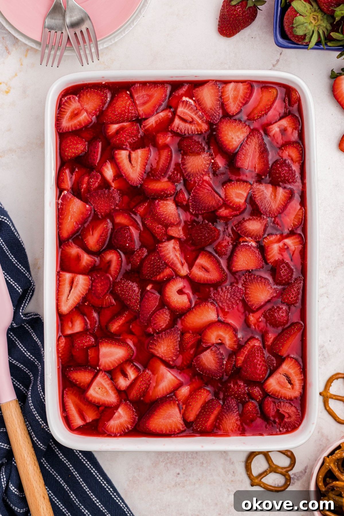 Strawberry Pretzel Dream 12 White baking dish filled with crust, strawberries, and j-ello topping.