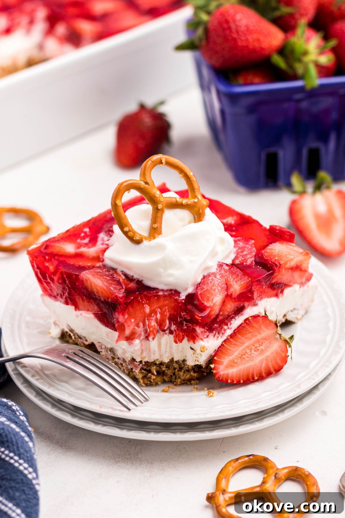 Strawberry Pretzel Dream 15 Slice of strawberry pretzel salad on small white plate with a fork on the side and a bite missing.