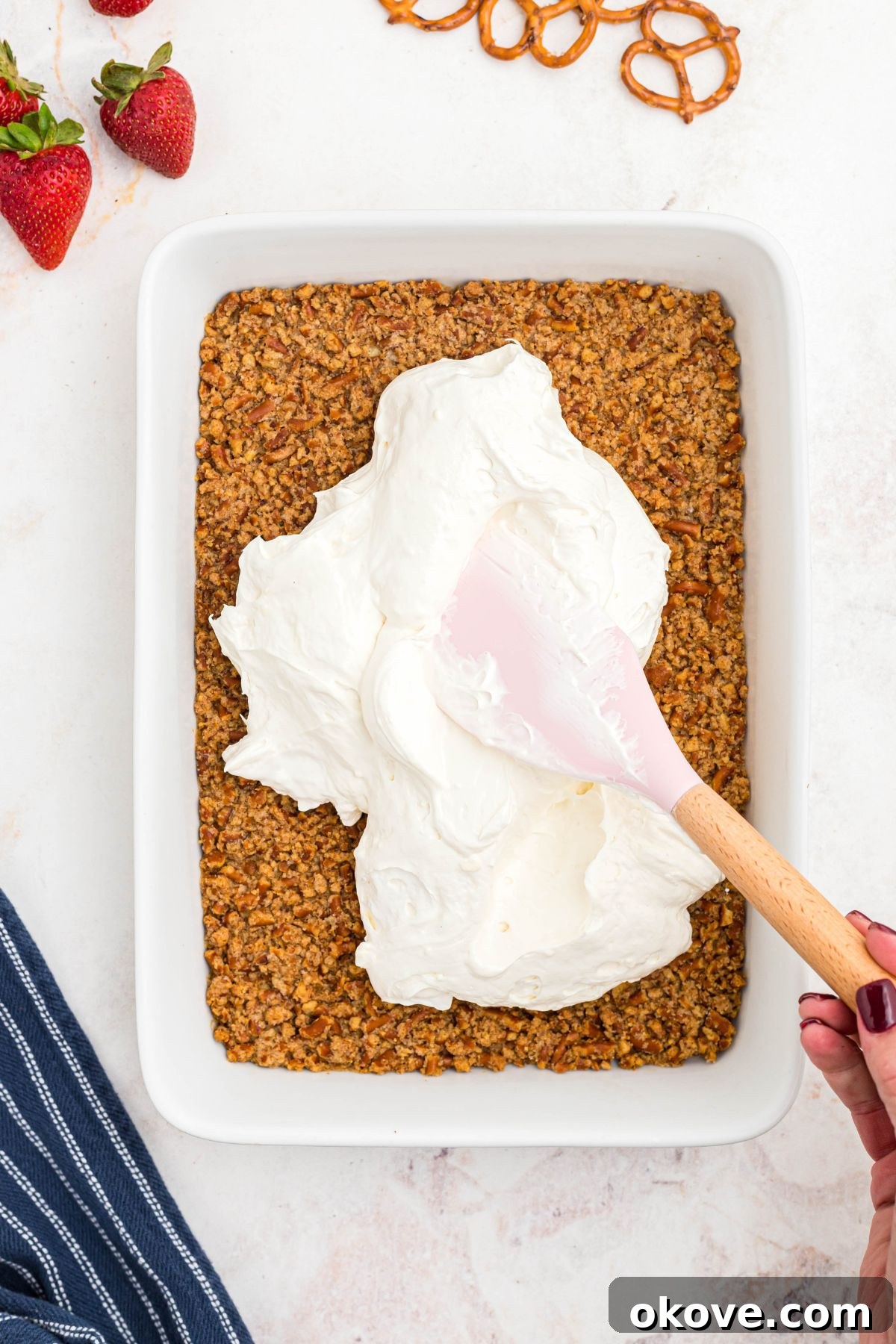 Strawberry Pretzel Dream 8 Whipped cream cheese topping being spread over pretzel crust.
