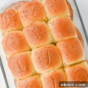 Melted butter with seasonings brushed on top of ham and cheese sliders.