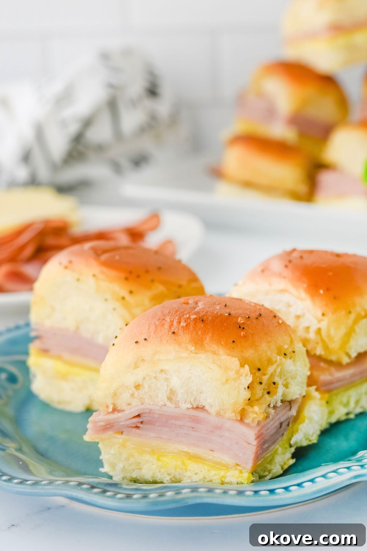 Freshly baked ham and cheese sliders presented on a blue plate, ready to be enjoyed.