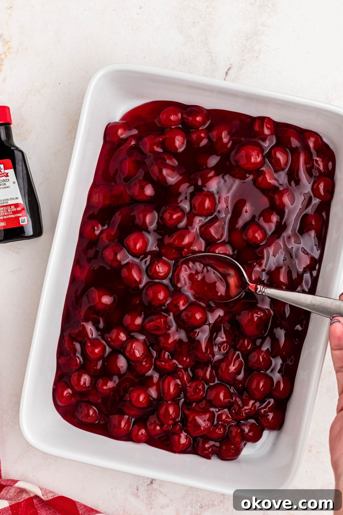 Cherry pie filling in a white casserole dish.