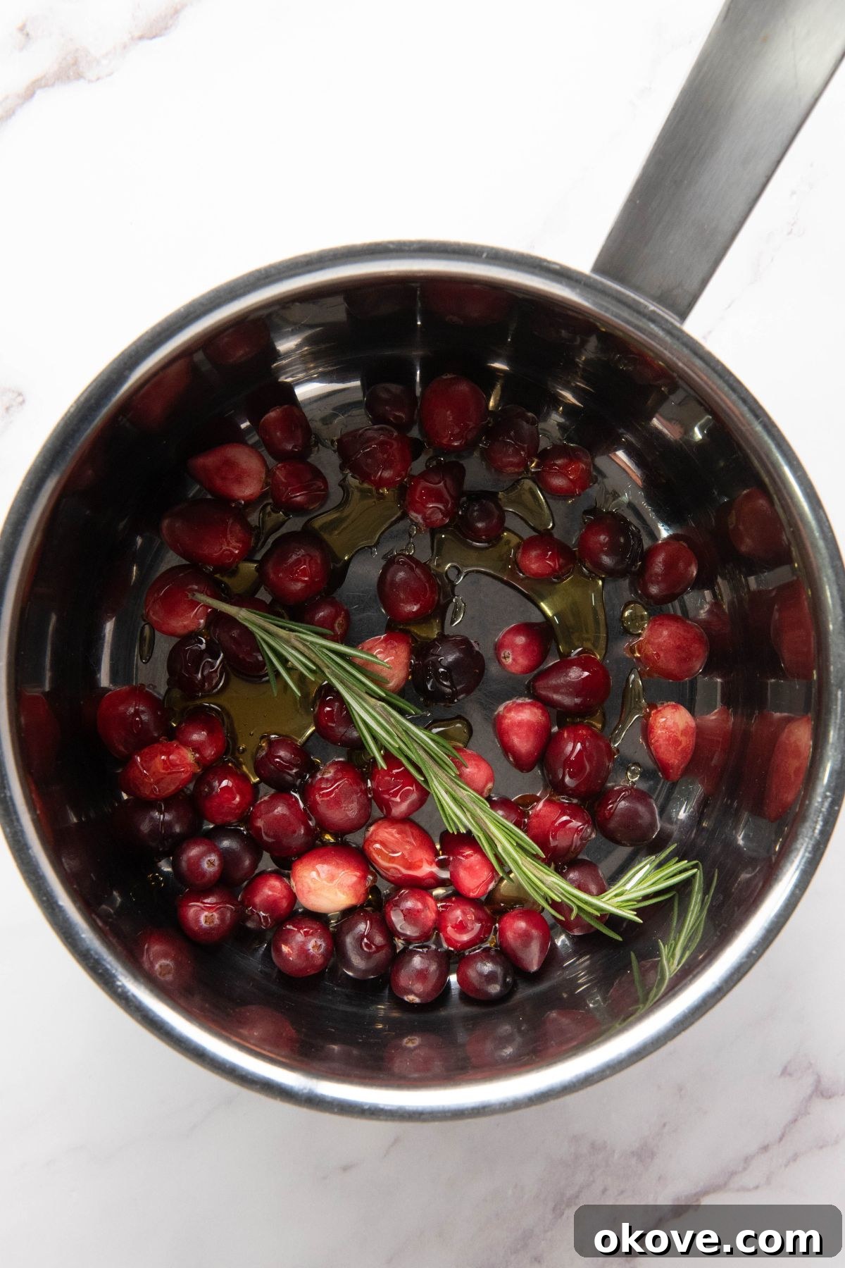 Warm Brie Delight 6 Fresh cranberries, golden honey, and fragrant rosemary sprigs simmering together in a small saucepan over medium heat, creating a rich, bubbling cranberry topping.