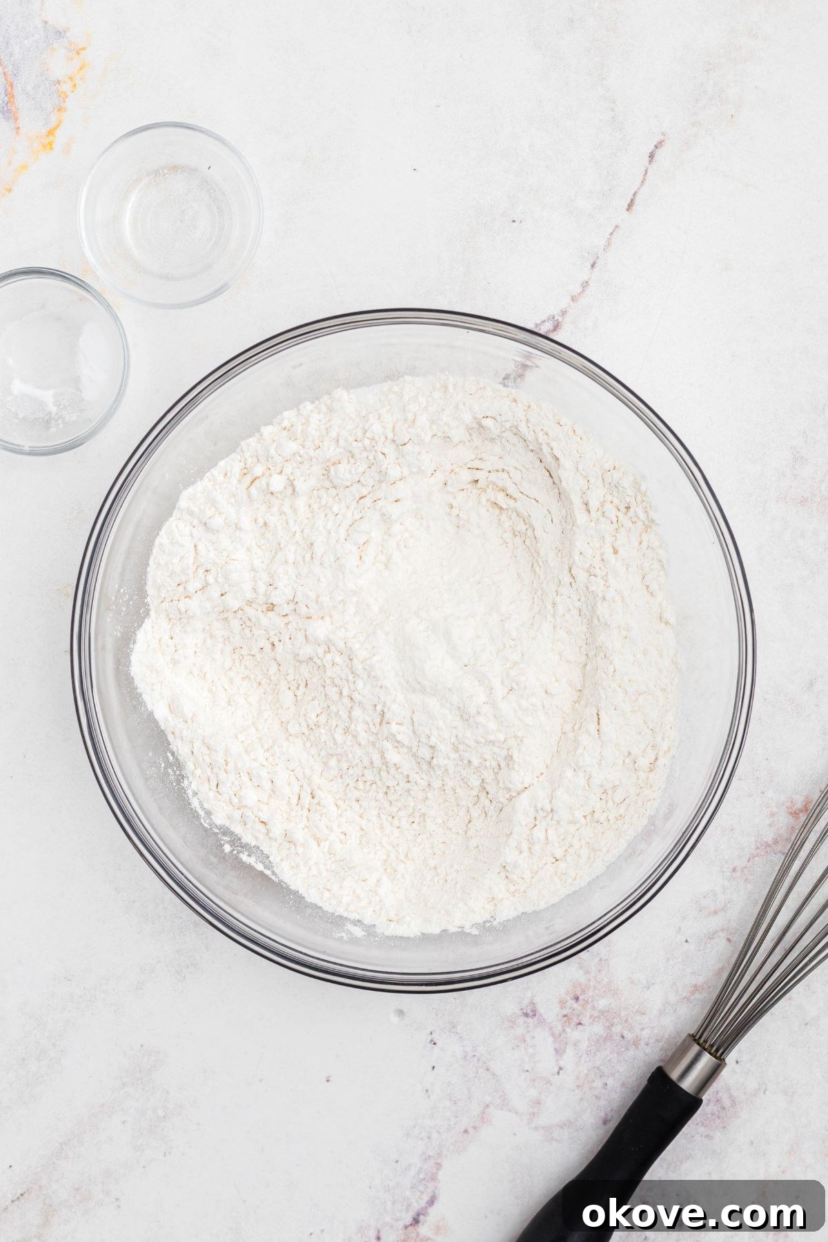 Dry ingredients, including flour, baking soda, and salt, perfectly combined in a clear glass mixing bowl.