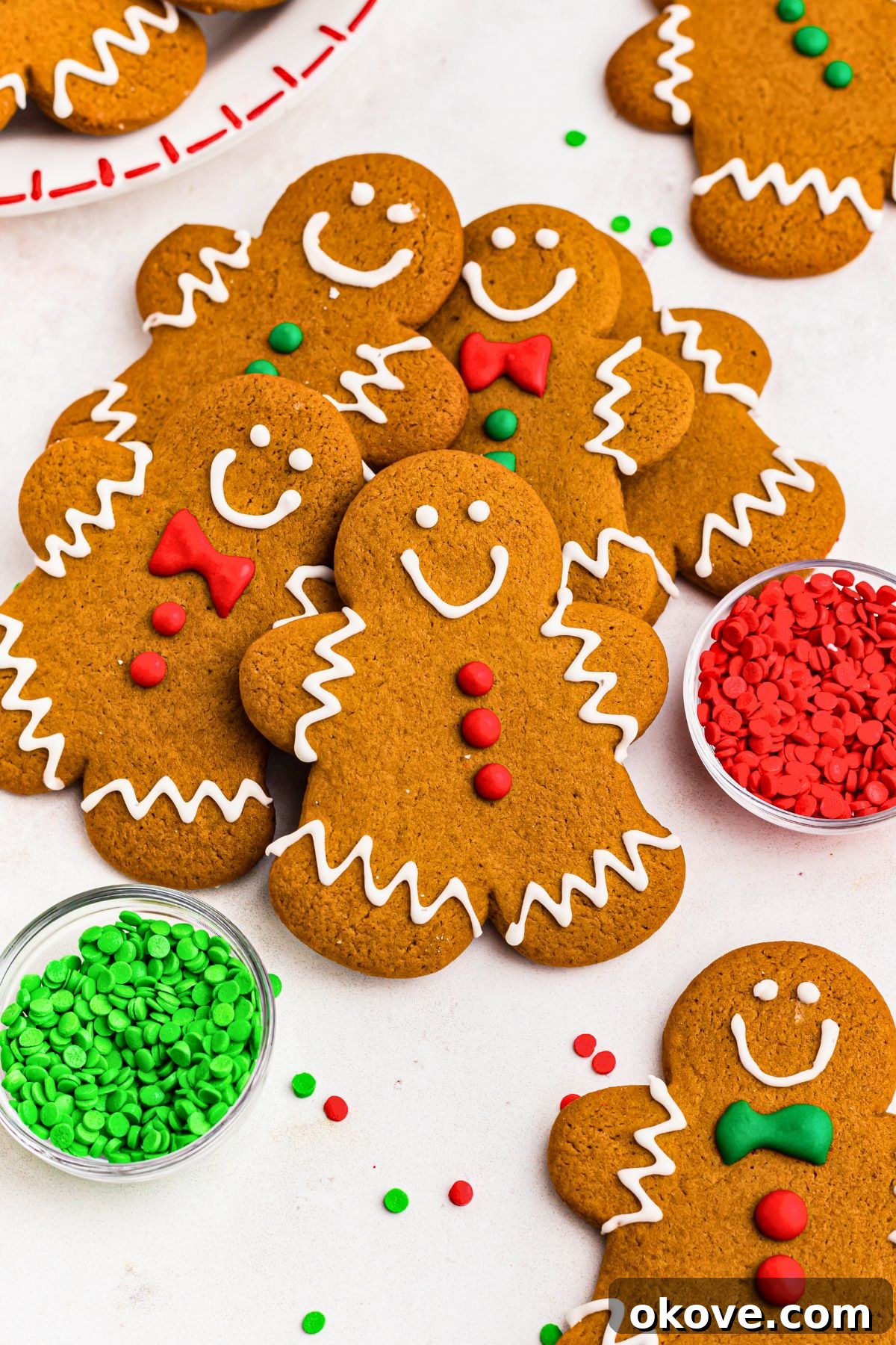 Festive Gingerbread Delights 2 Golden brown gingerbread men cookies stacked on a marble table with holiday sprinkles scattered around the table.